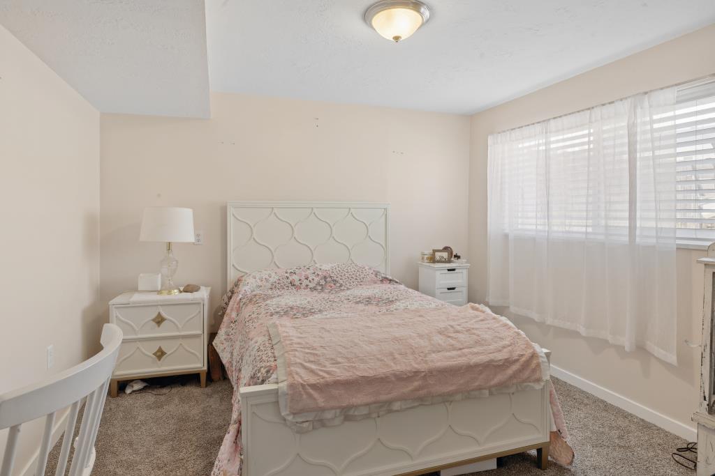 Bedroom featuring soft neutral wall paint and a window with blinds and sheer curtains