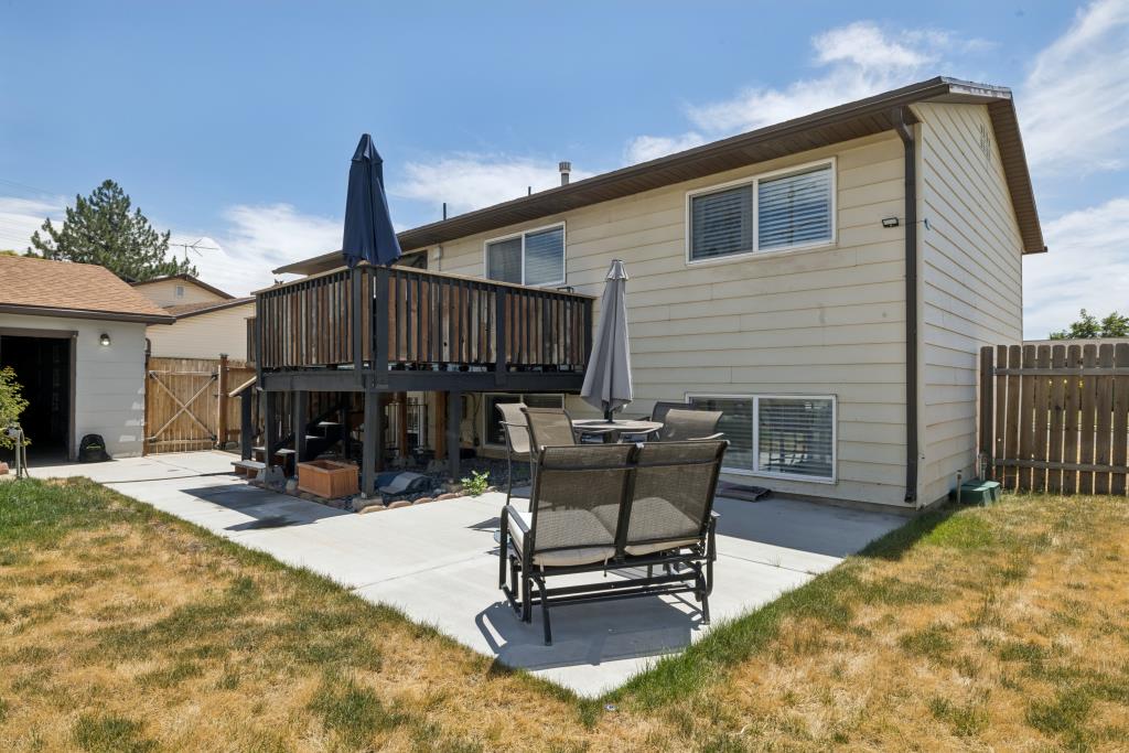 Rear exterior with a raised wood deck, a concrete patio, and a detached garage