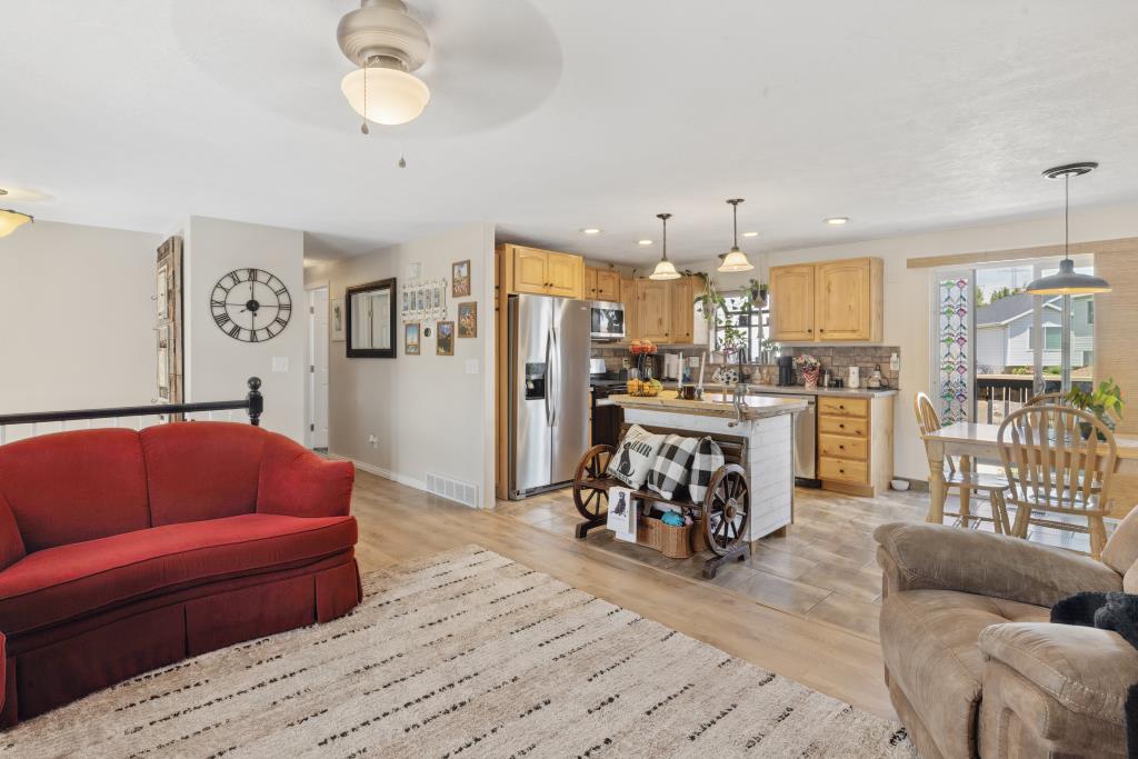 Open-concept living area featuring a kitchen with wood-finish cabinetry, stainless steel appliances, and a central island.
