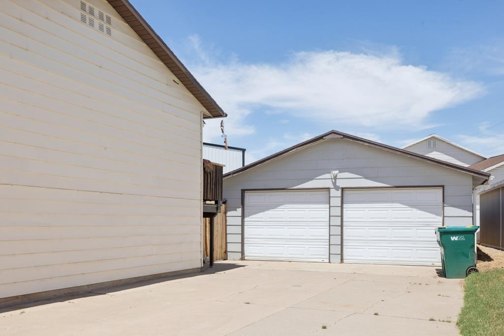 Two-car garage with white paneled doors and a light gray exterior, featuring a concrete driveway
