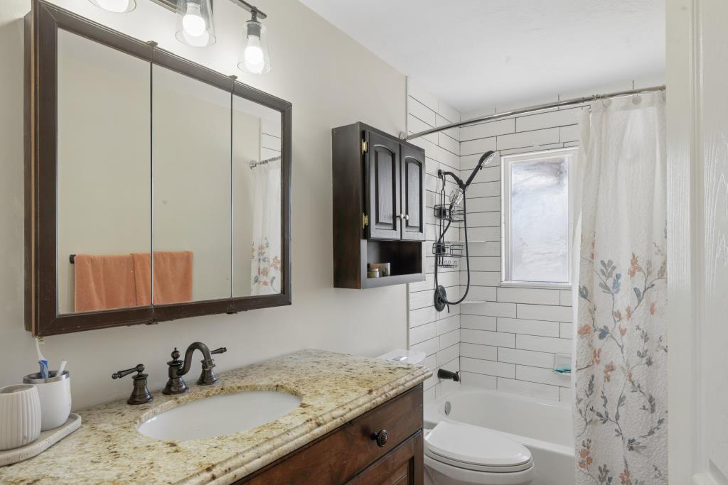 Bathroom featuring a granite-finish countertop, wood-finish vanity, and bronze-finish fixtures