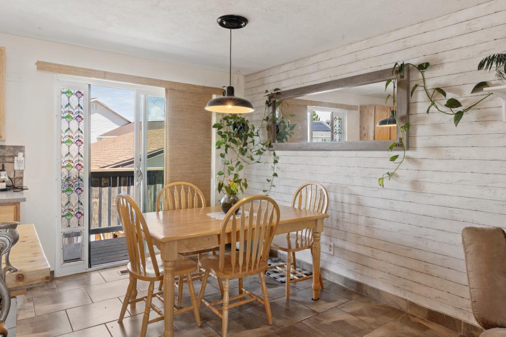 Dining area featuring a wood-finish dining table and chairs, tile flooring, and a shiplap accent wall