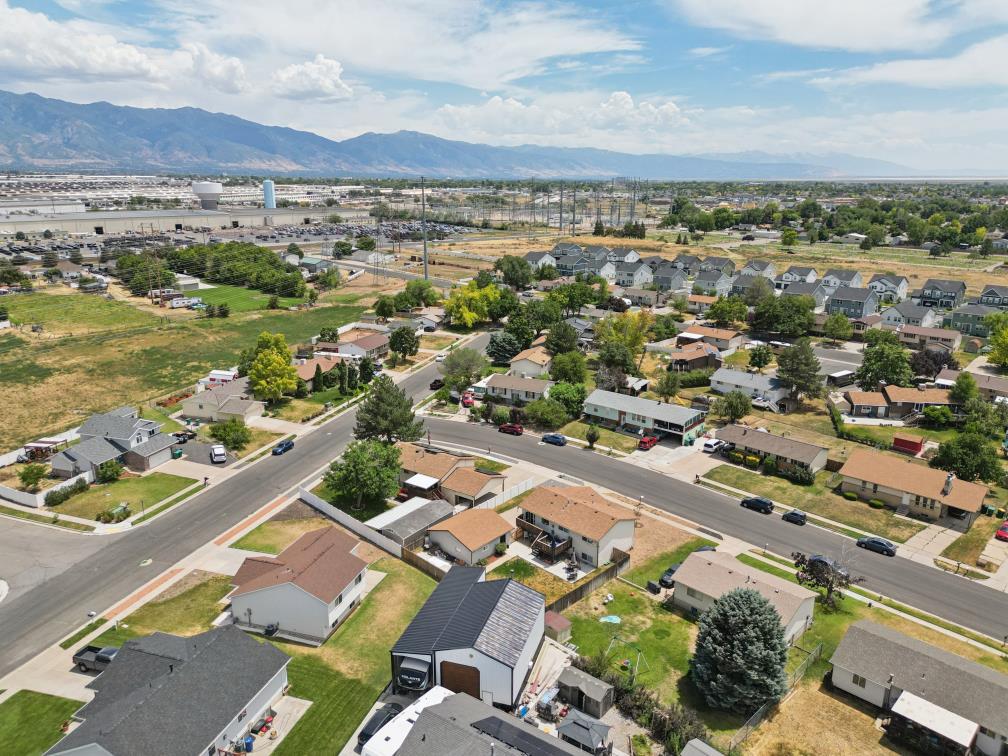 Aerial perspective of a residential street with single-family homes, mature trees, and mountainous scenery in the distance