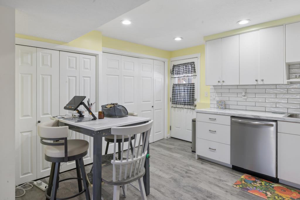 Kitchen area featuring white cabinetry with silver hardware, subway tile backsplash, and light-toned countertops