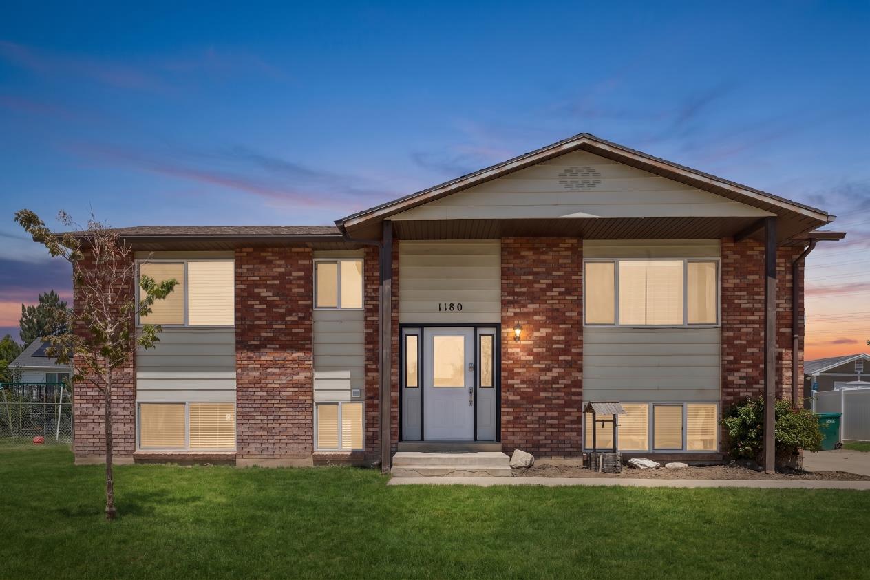 Two-story residential exterior featuring brick and horizontal siding accents, a prominent front entry with sidelights, a covered porch, and a manicured lawn (Digitally enhanced to show lawn potential)