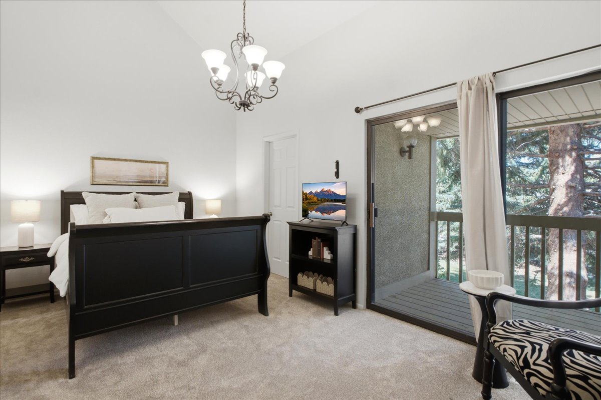 Vaulted ceilings elevate this primary suite, with direct access to a private tree-lined balcony.