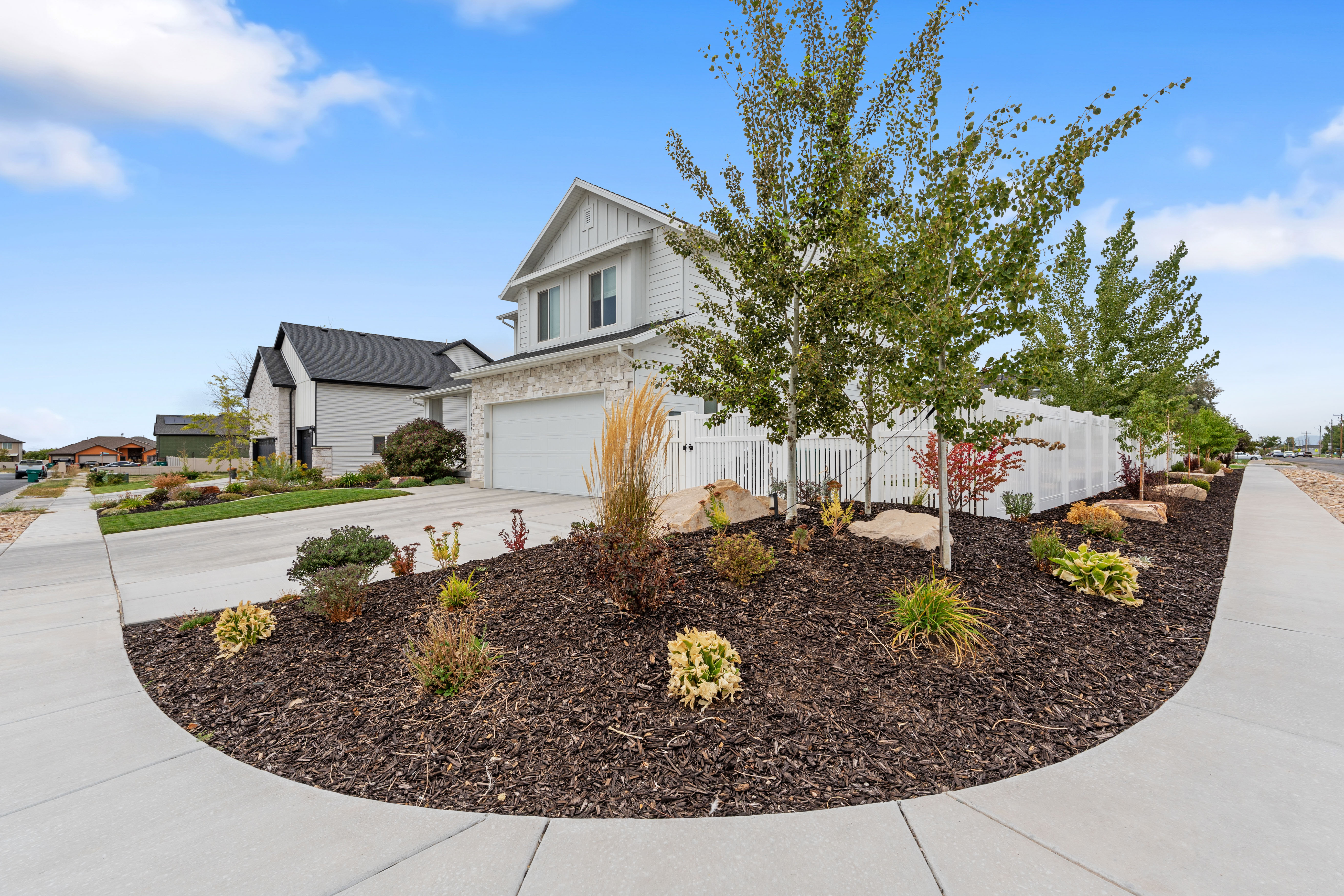 Contemporary property exterior featuring white siding, stone accents, and a prominent two-car garage