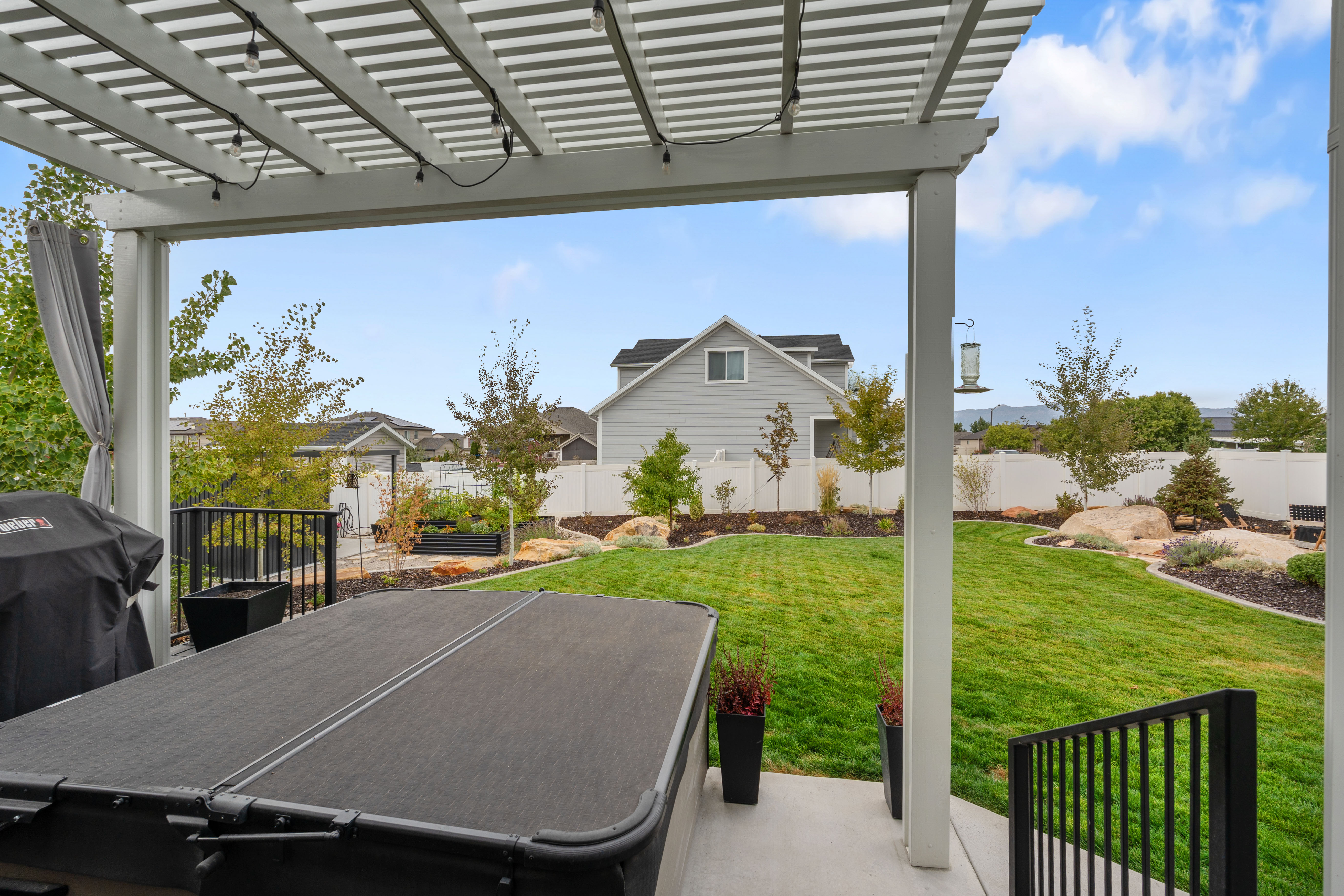 Covered patio featuring a hot tub, string lighting, and a privacy curtain