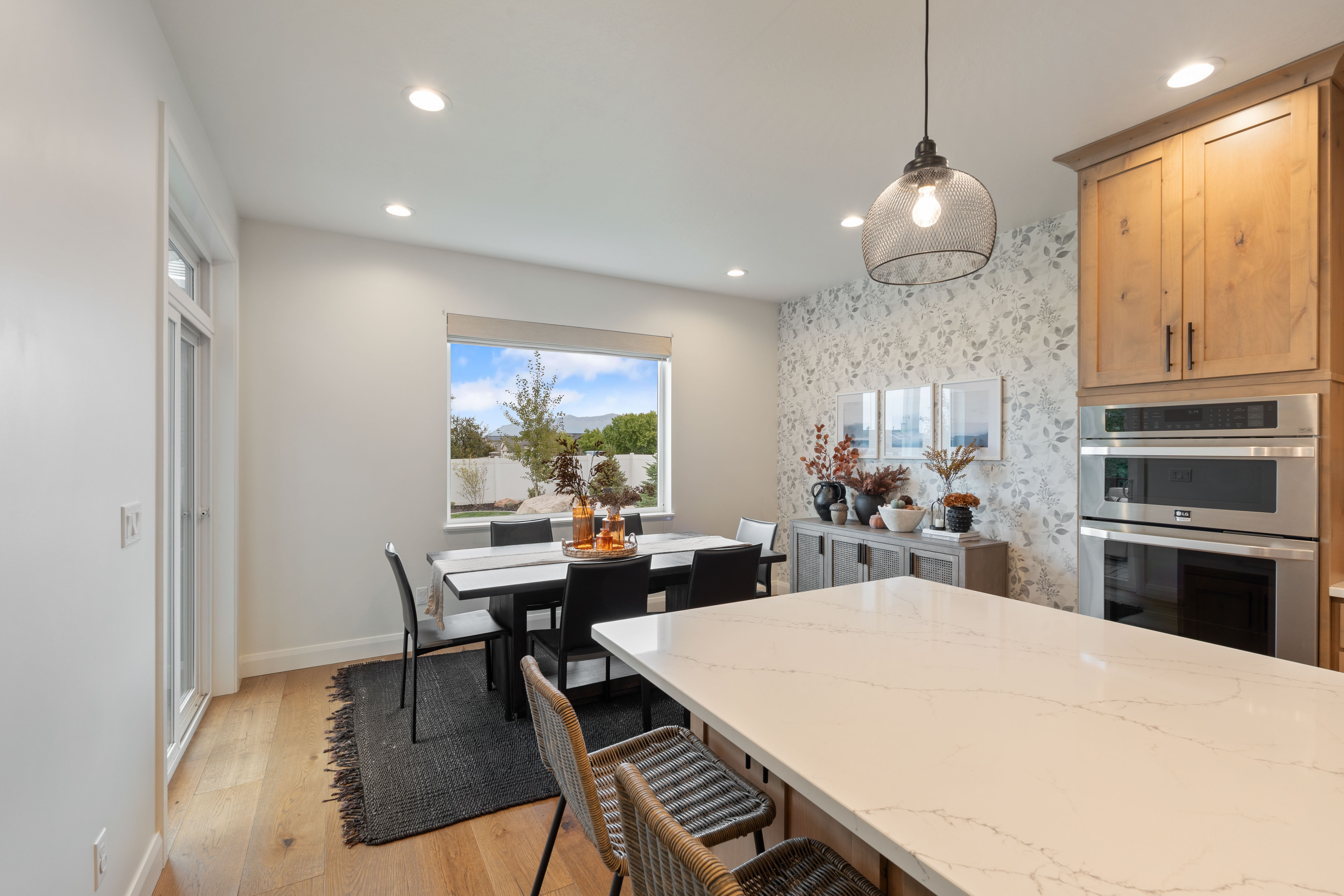 Open-concept kitchen and dining area featuring light wood-finish flooring, recessed lighting, and a prominent kitchen island with a light-toned countertop