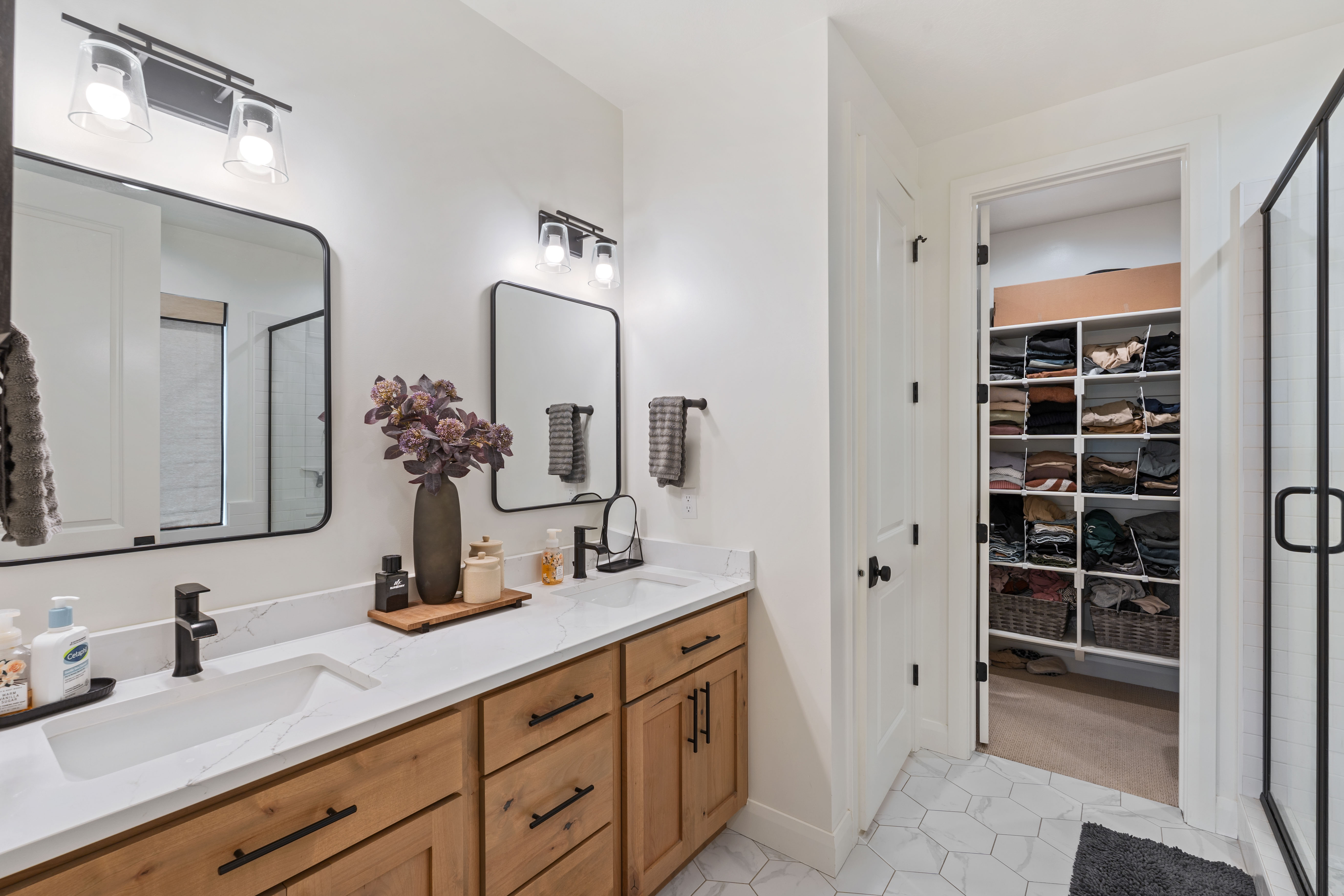 Master on Main - Double vanity with wood-finish cabinetry, white quartz-style countertops, and matte black fixtures