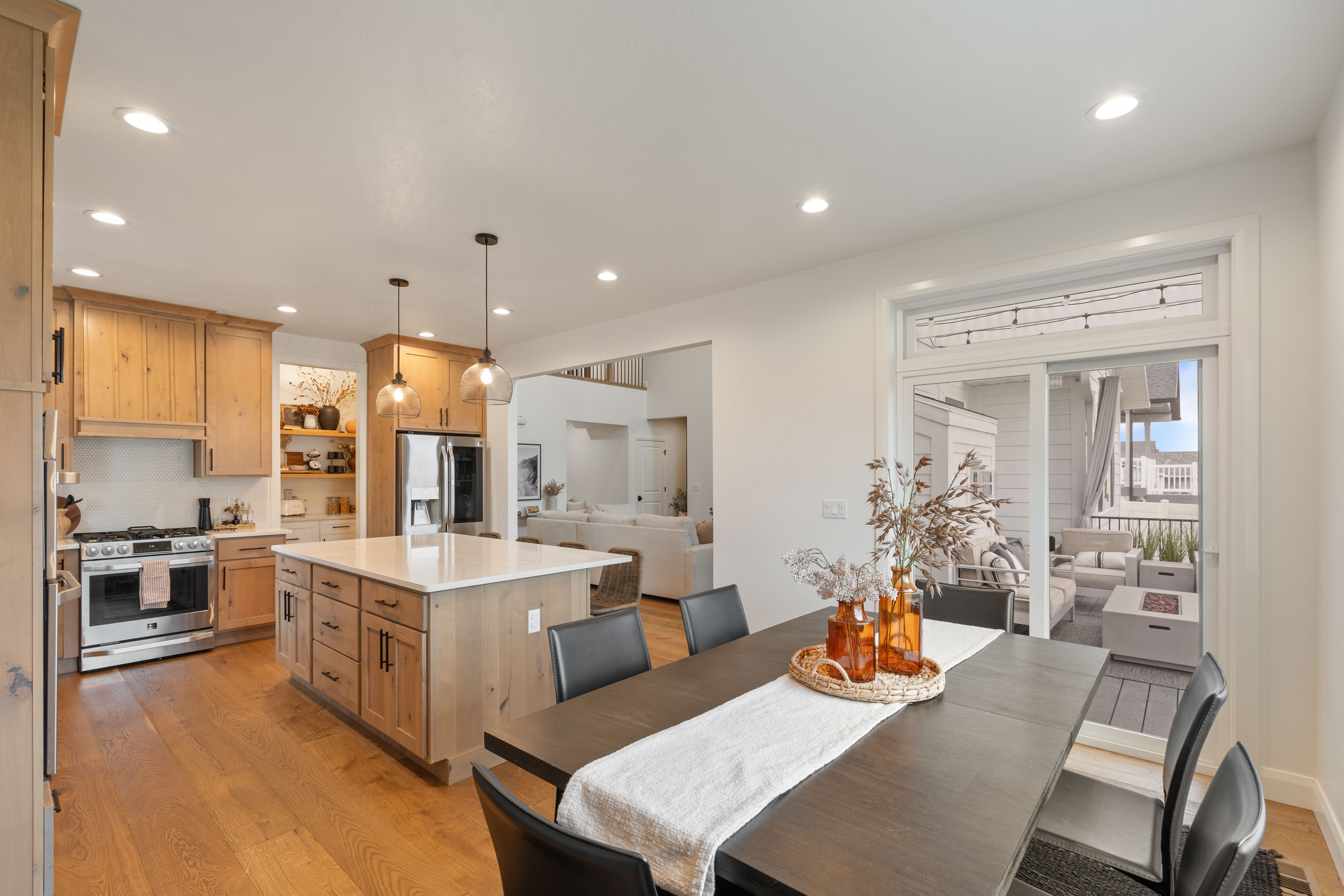 Open-concept kitchen and dining area featuring light wood-finish cabinetry, stainless steel appliances, a center island with white countertop, and recessed lighting