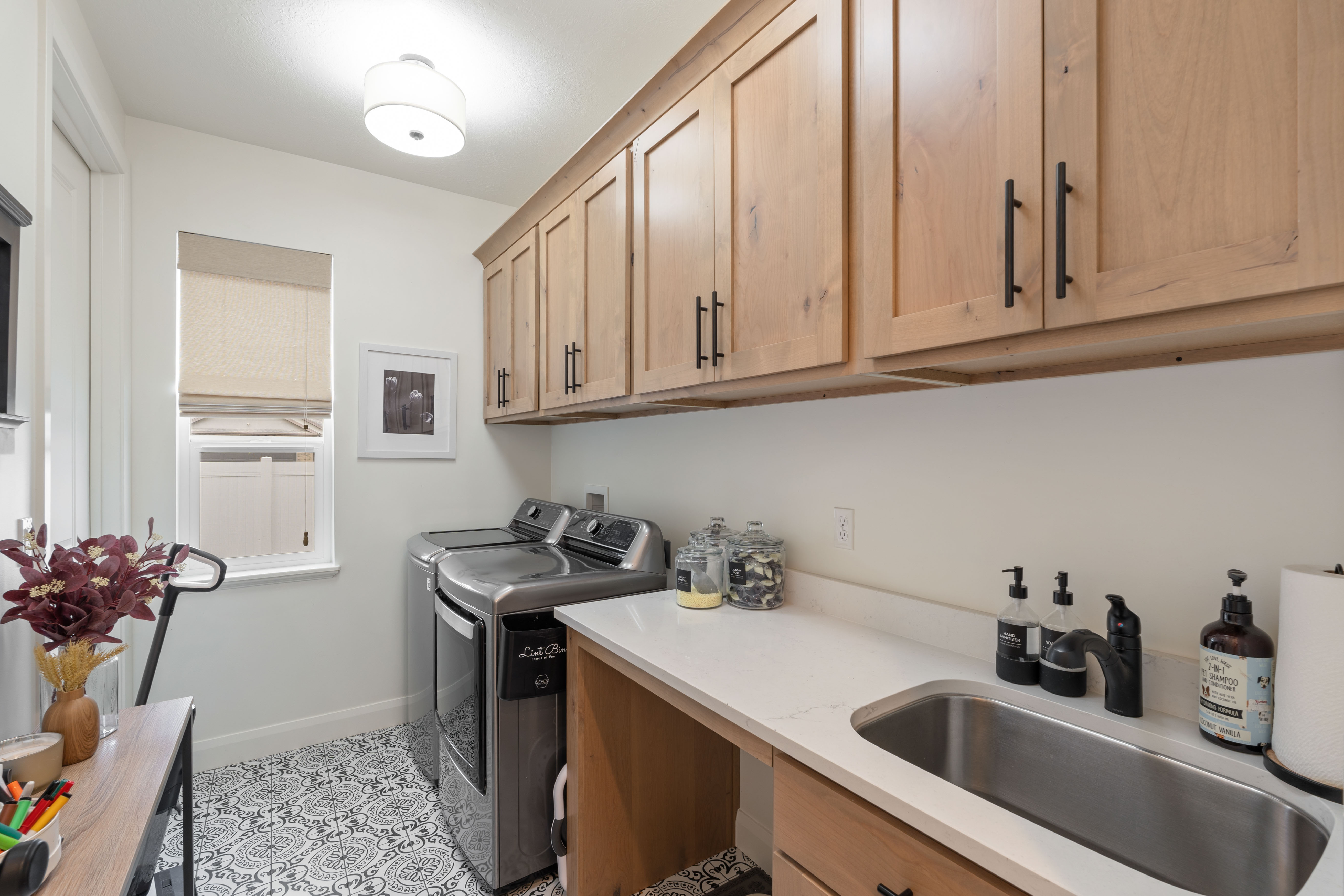Laundry room with wood-finish cabinetry, a white countertop, and a stainless steel sink