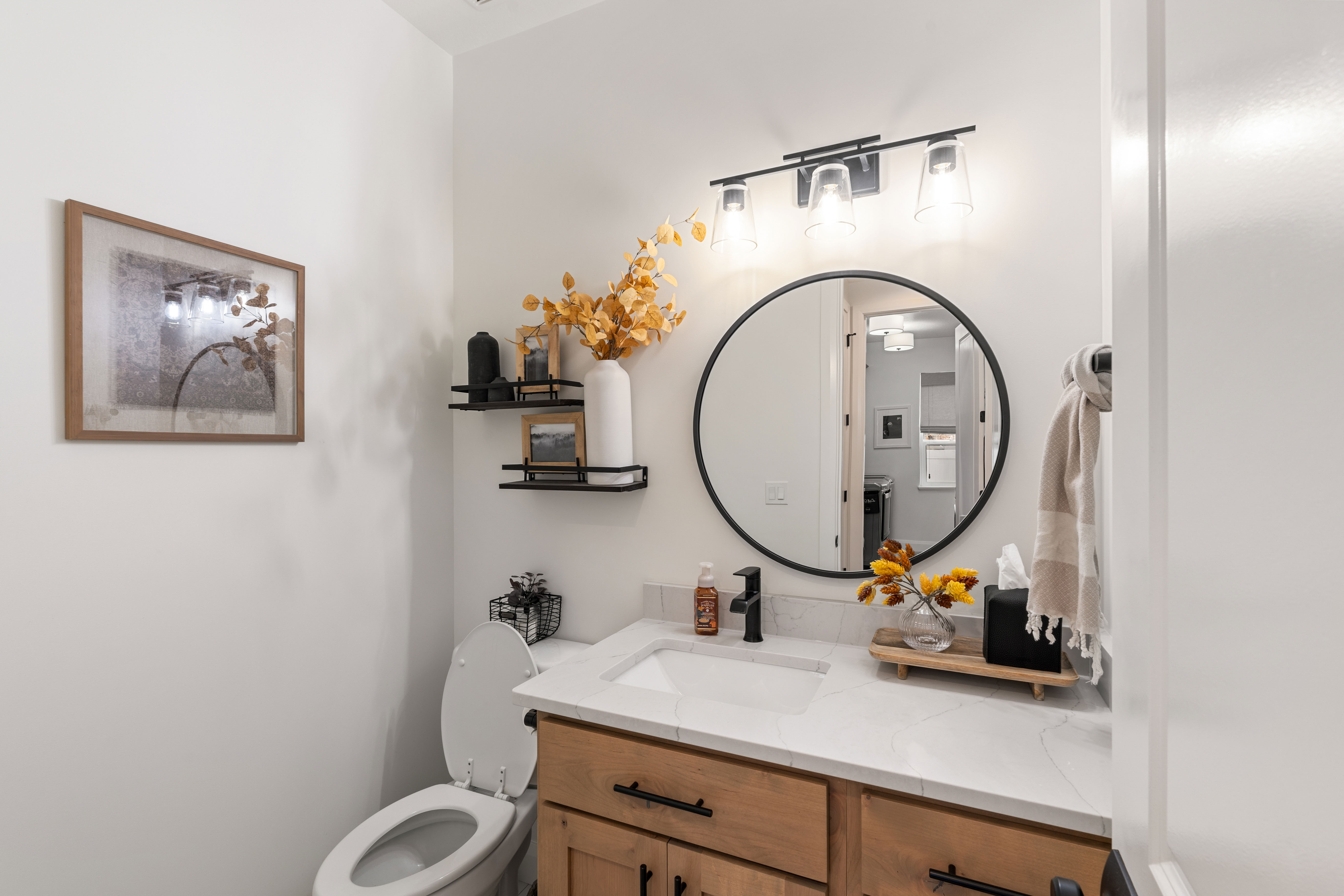 Bathroom featuring a wood-finish vanity with black hardware, white countertop, and an undermount sink