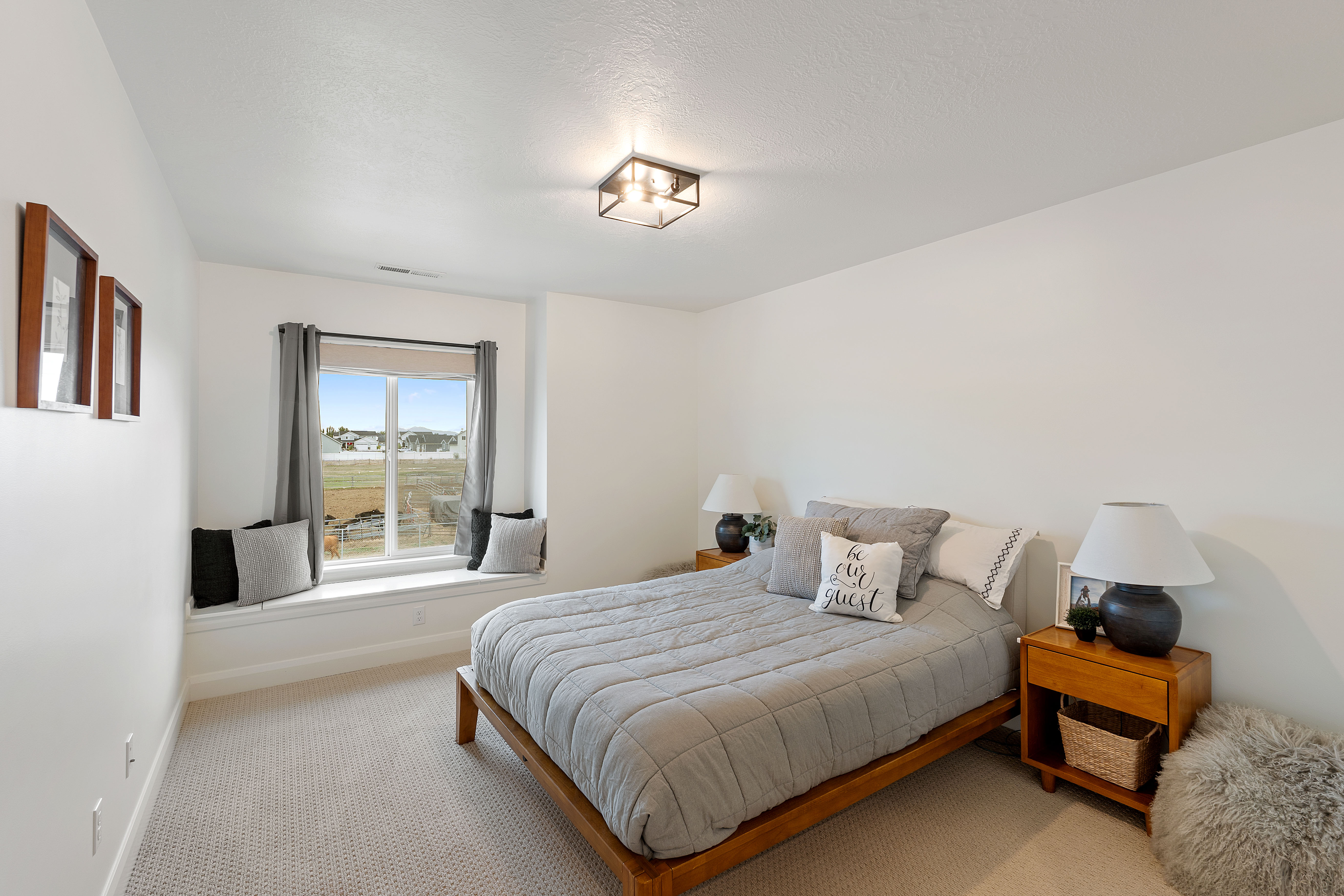 Bright bedroom featuring a recessed window seat, neutral carpeting, and a contemporary ceiling light fixture