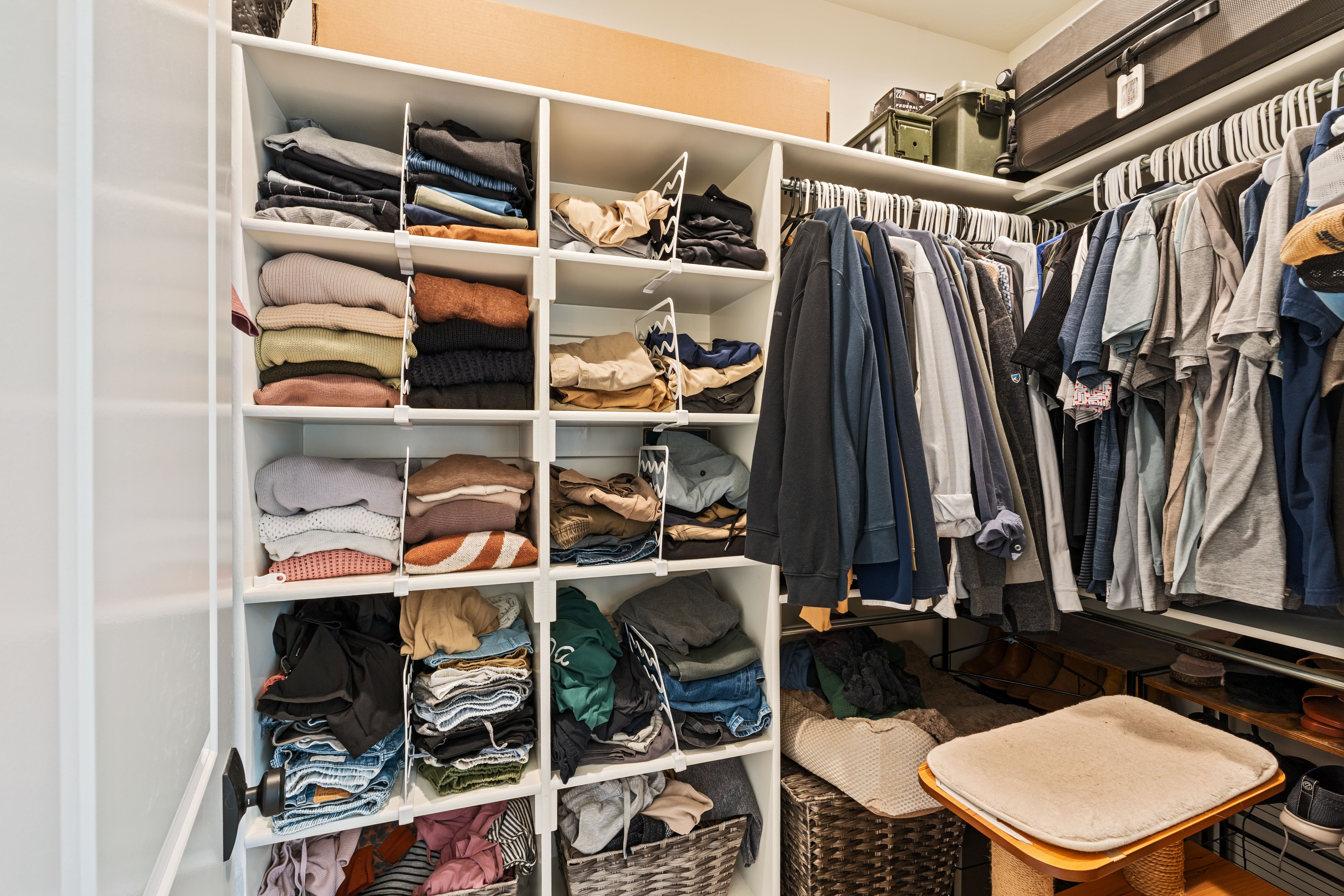 Master walk-in closet featuring built-in white shelving, multiple hanging rods, and integrated storage solutions