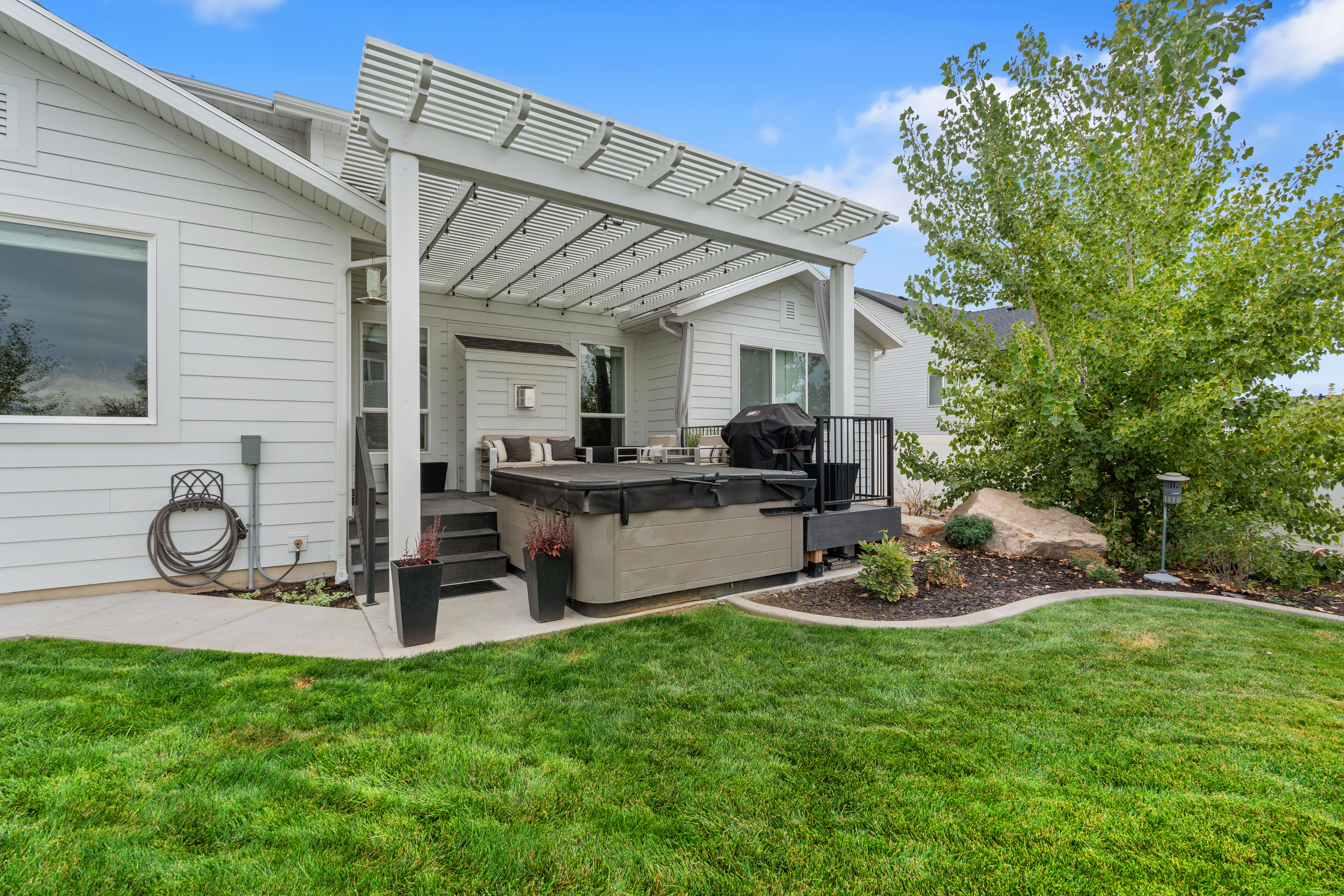 Hot Tub and Expansive backyard featuring a lush lawn and a concrete patio