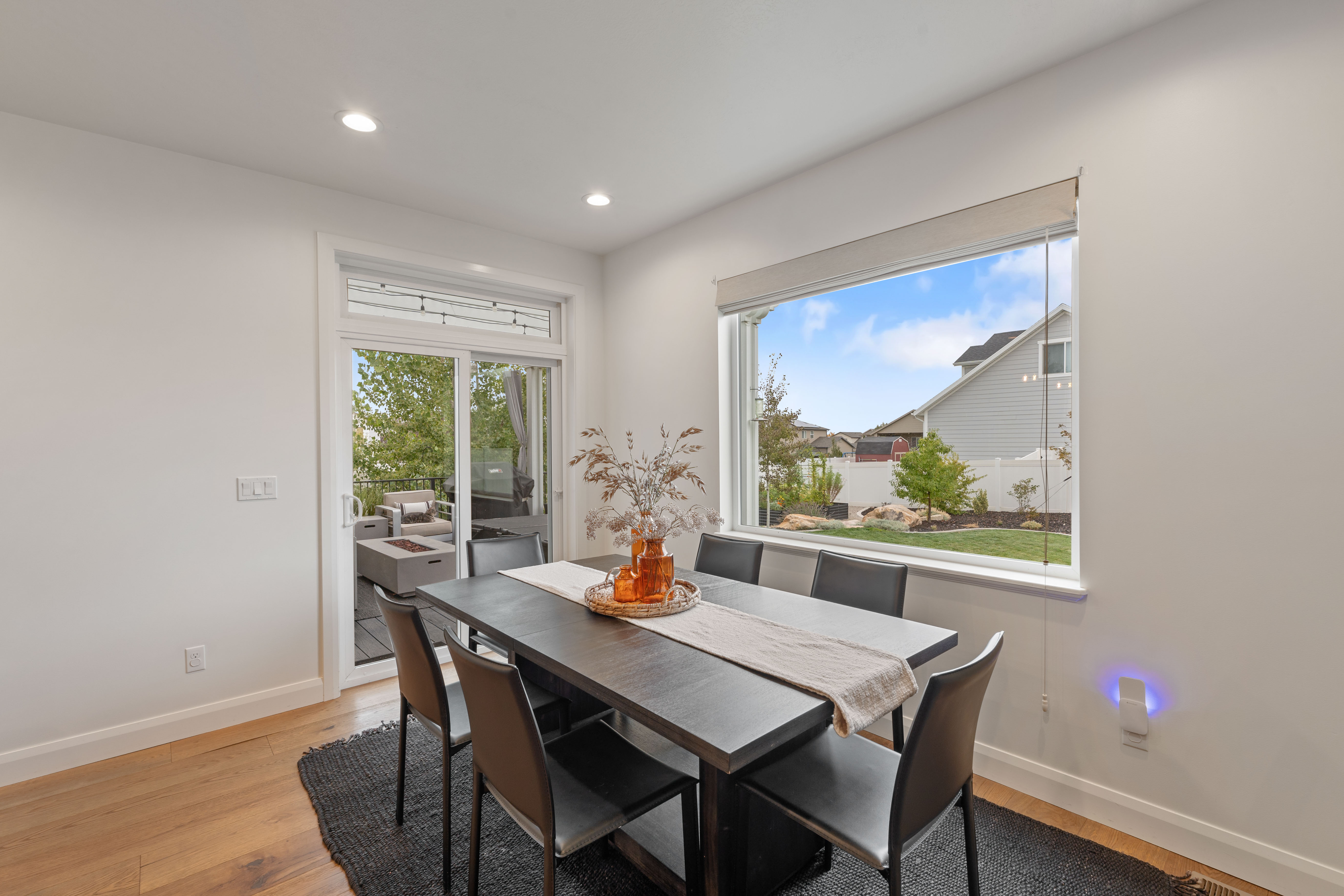 Bright dining area featuring wood-finish flooring, recessed lighting, and a wide window with a roller shade