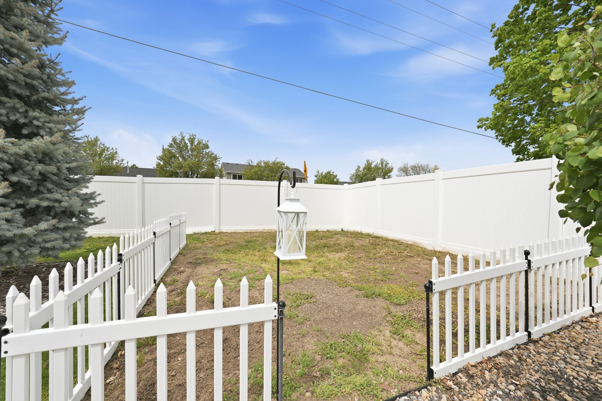 Enclosed backyard featuring a white privacy fence, an interior white picket fence, and mature perimeter trees