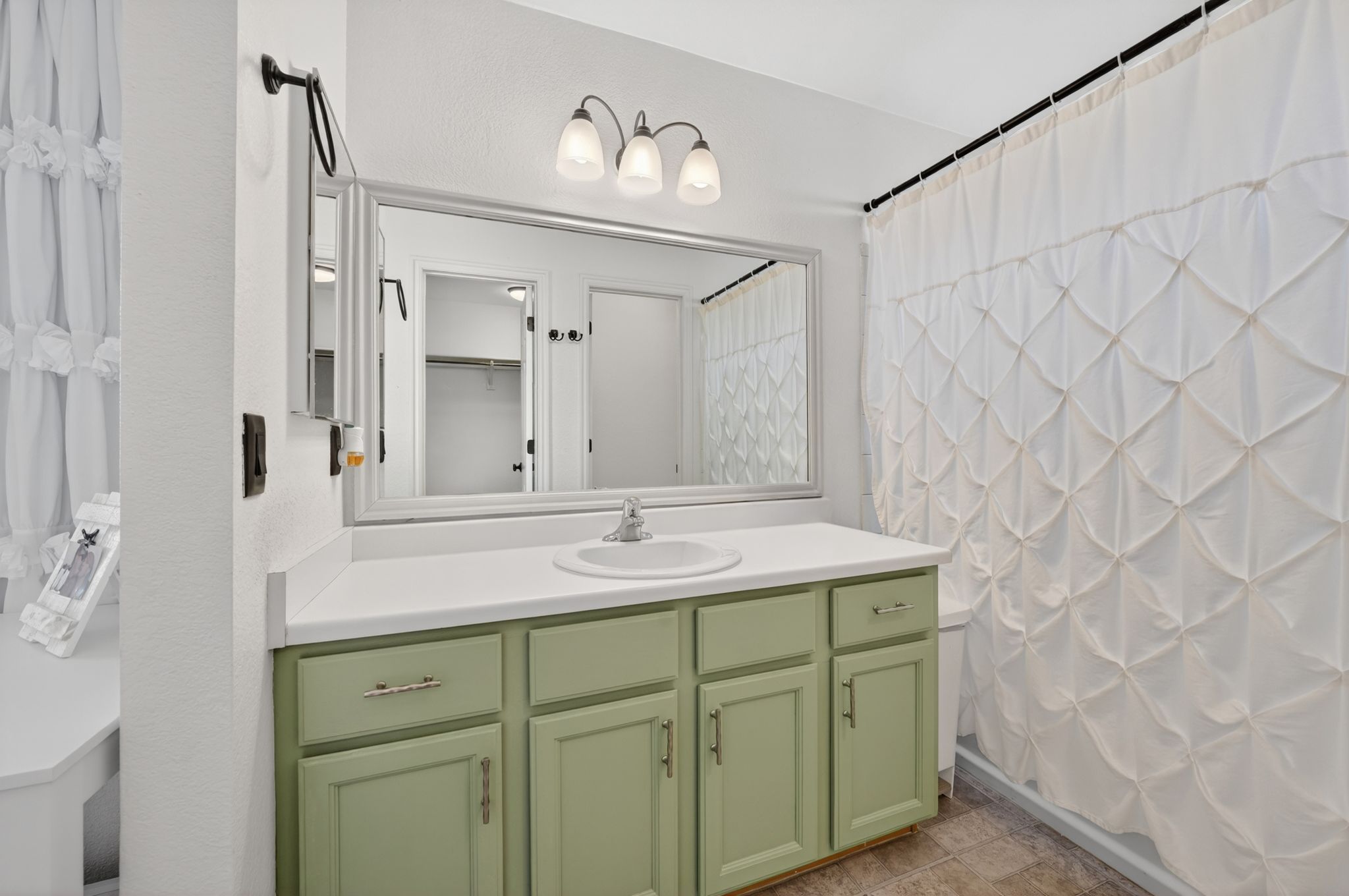 Bathroom featuring a single vanity with a mint green cabinet base, a white countertop, and a basin sink