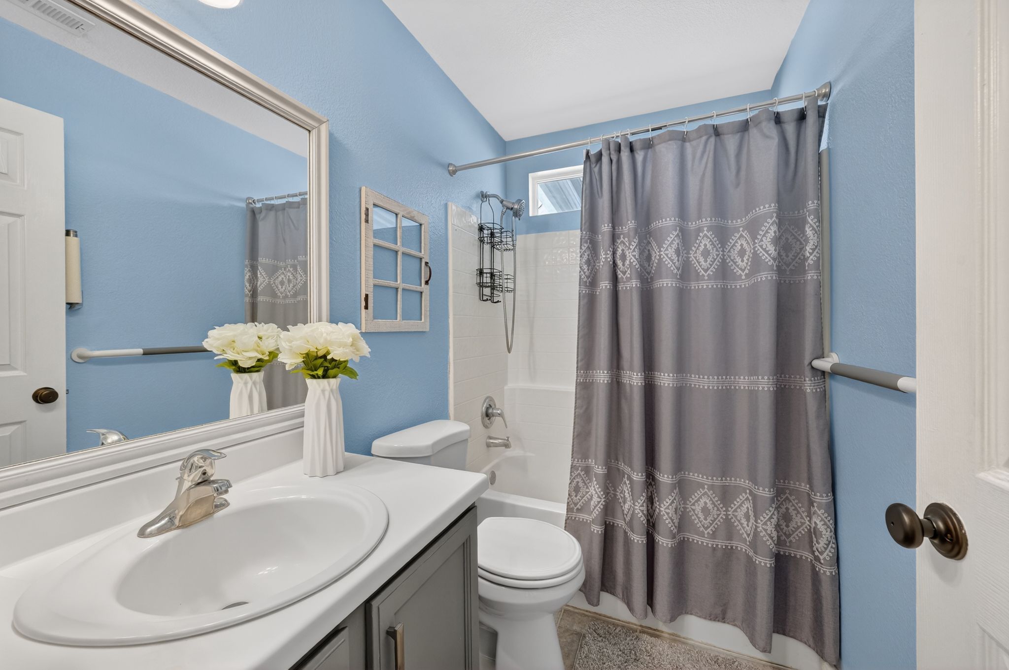 Bathroom featuring a single vanity with a white countertop and undermount sink, brushed nickel faucet, and a large framed mirror