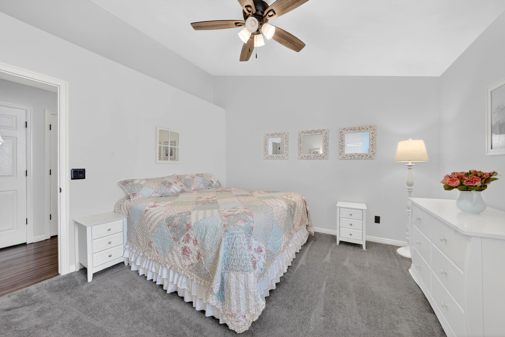 Vaulted ceiling room featuring a ceiling fan with light fixture, plush gray carpeting, and light gray wall paint