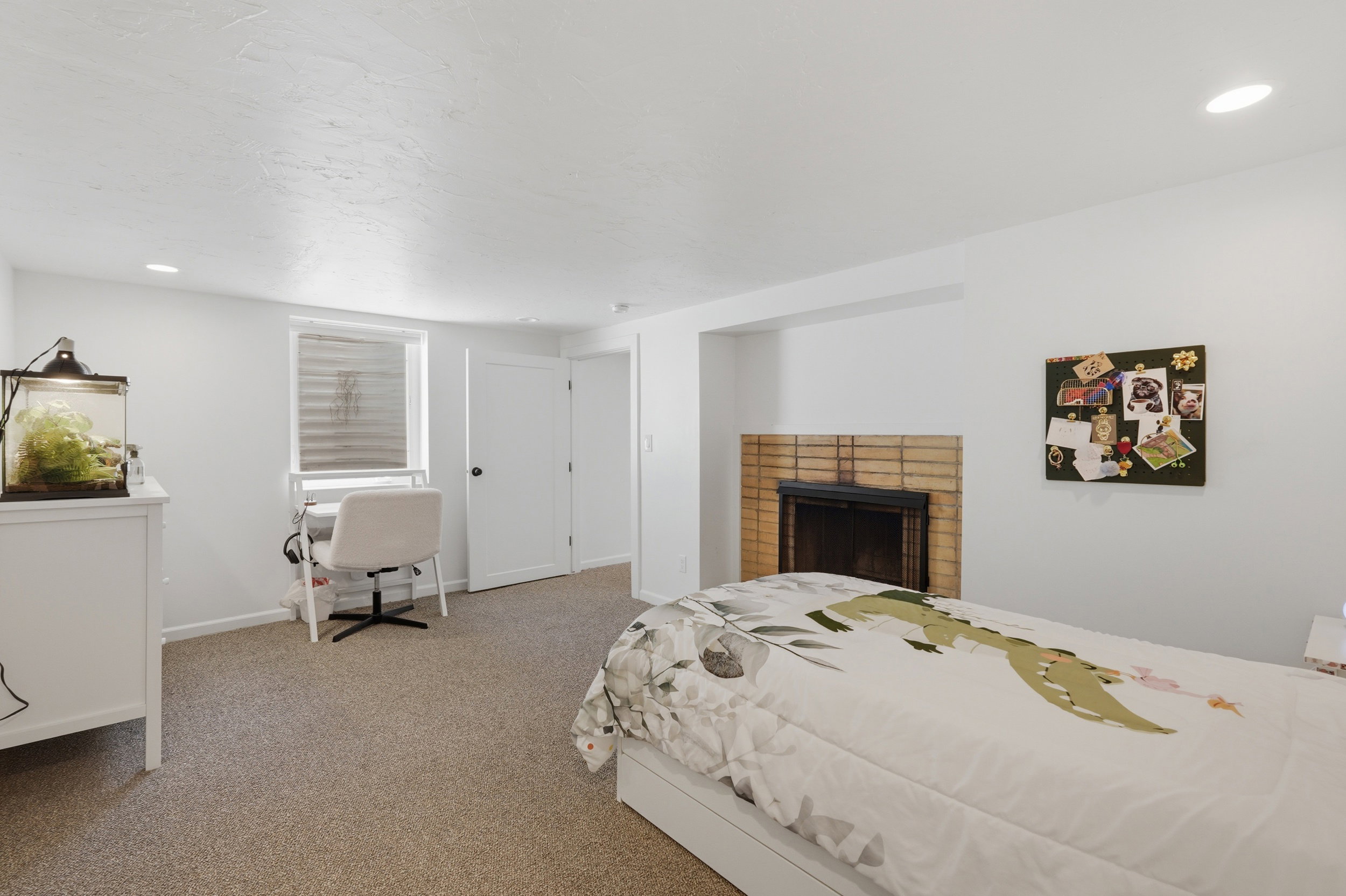 Recessed lighting illuminates a carpeted room featuring a brick fireplace with a black insert