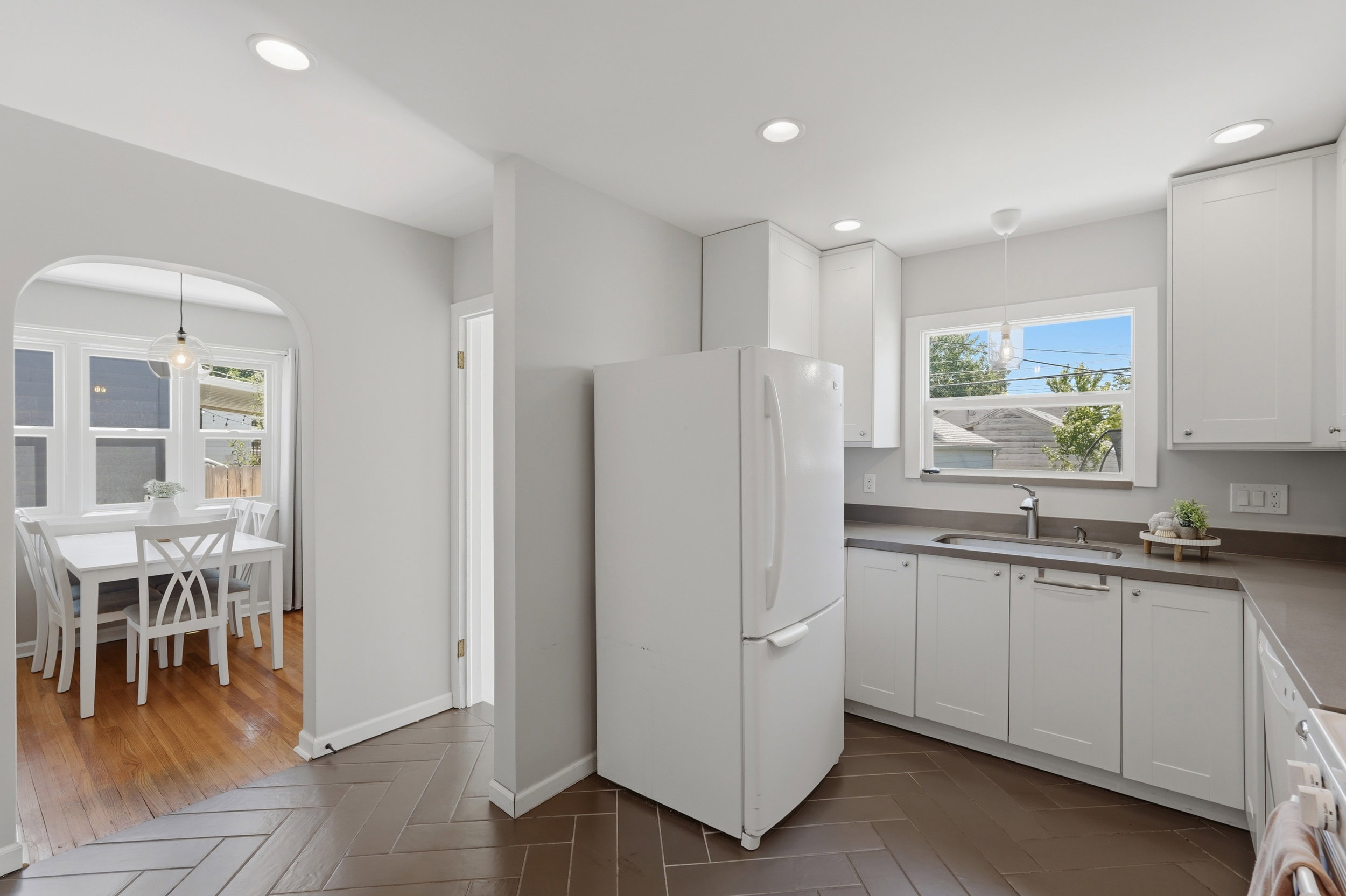 Kitchen featuring white cabinetry, a single basin sink with a gooseneck faucet, gray countertops, and herringbone-patterned tile flooring