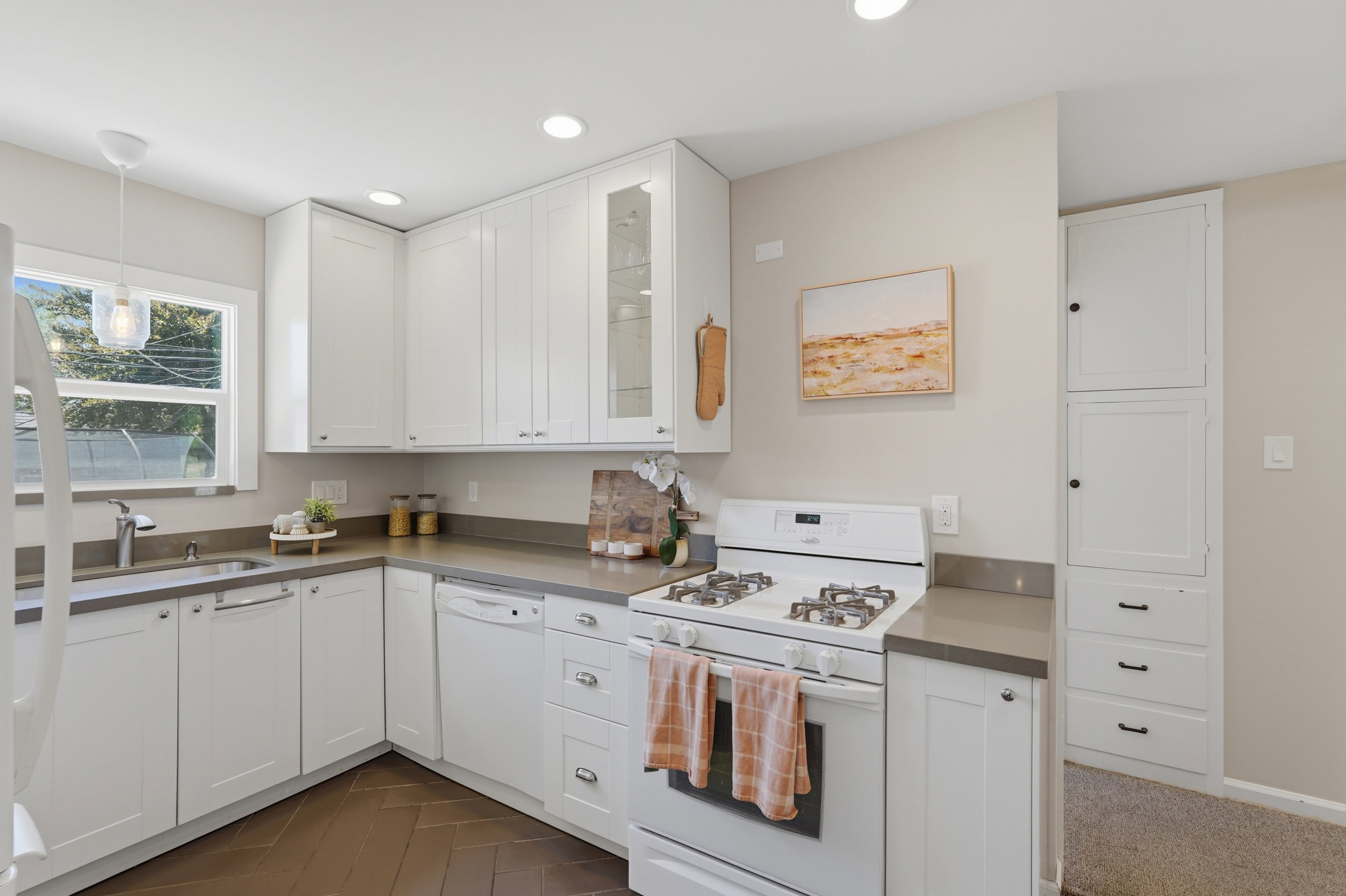 Modern kitchen with white shaker-style cabinetry, dark stone countertops, recessed lighting, and wood-finish flooring