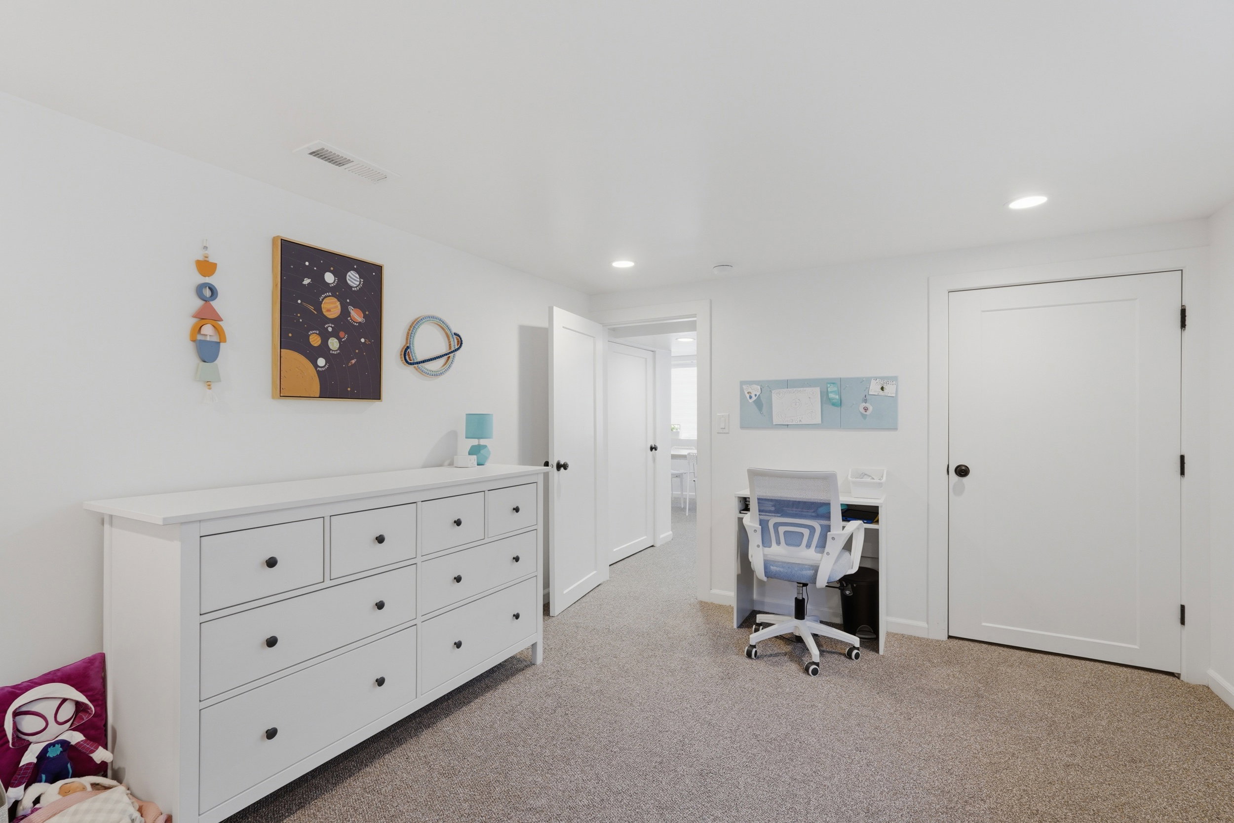 Recessed lighting illuminates this room, featuring light gray carpeting and white walls