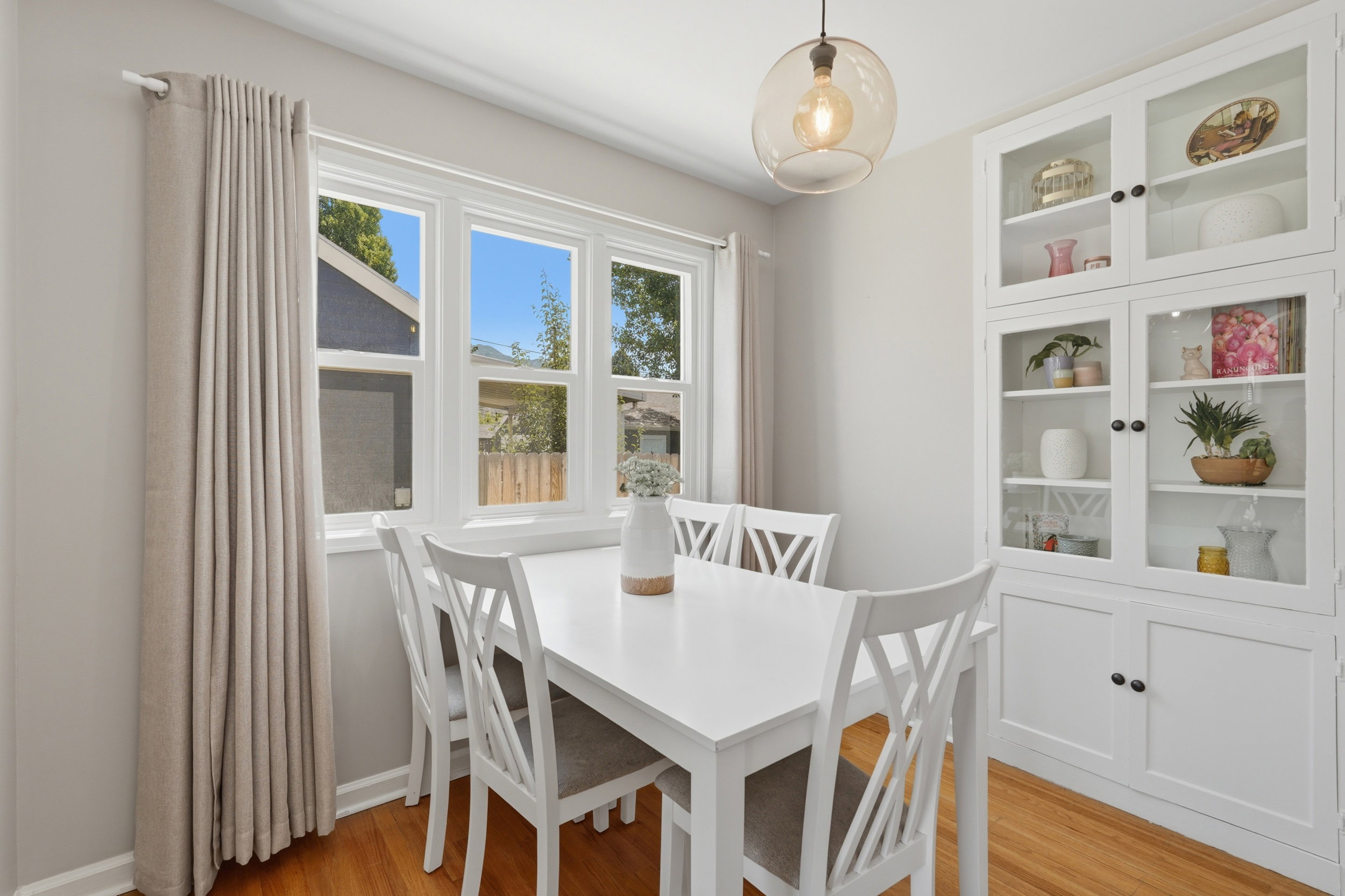 Built-in cabinetry with glass-front doors, hardwood flooring, and a multi-pane window