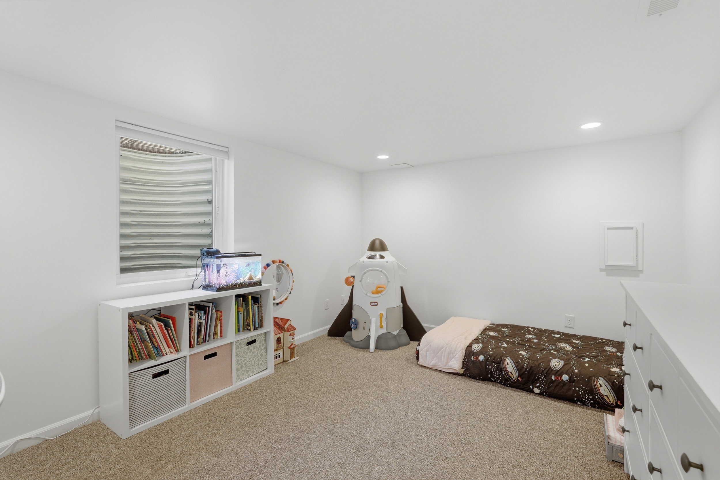 Carpeted room featuring a white painted wall, a single window with a window well, and recessed ceiling lighting