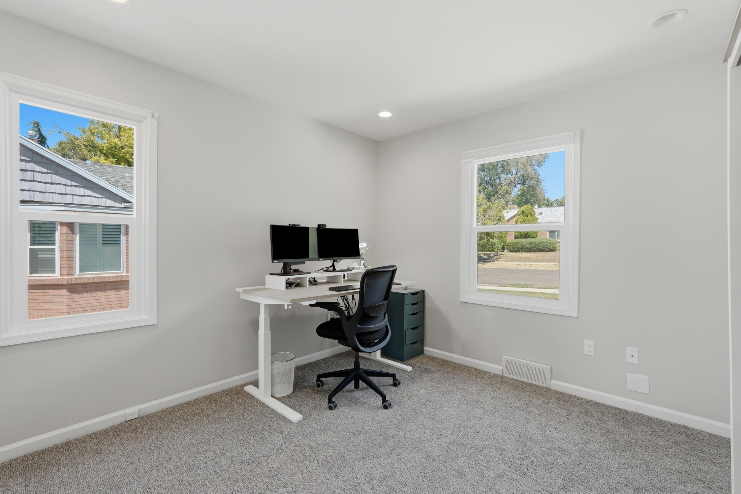 Bright interior space featuring two windows with white trim, light gray wall paint, and recessed ceiling lighting