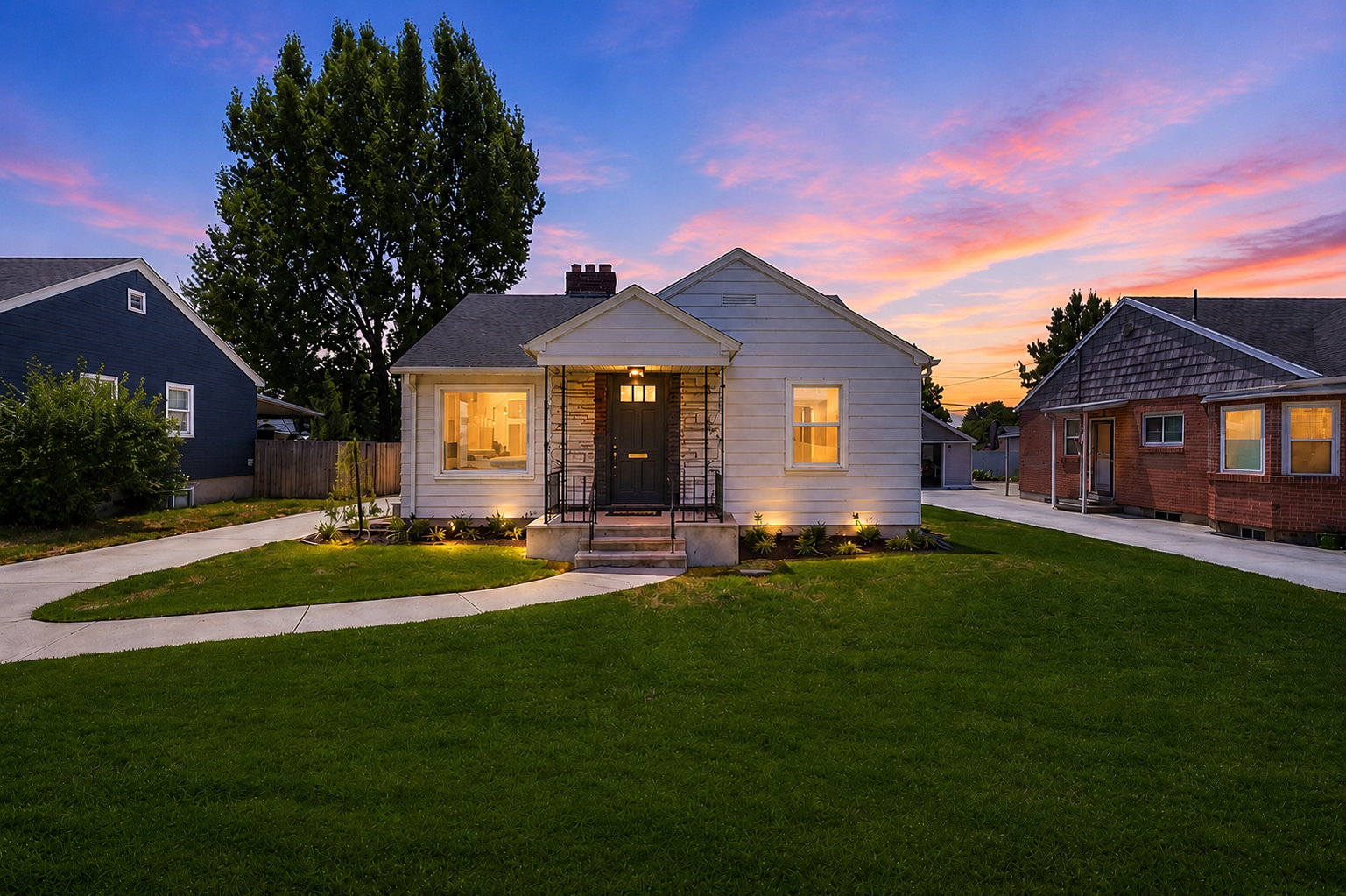 Cottage-style home featuring a stone facade, dark entry door, and exterior lighting