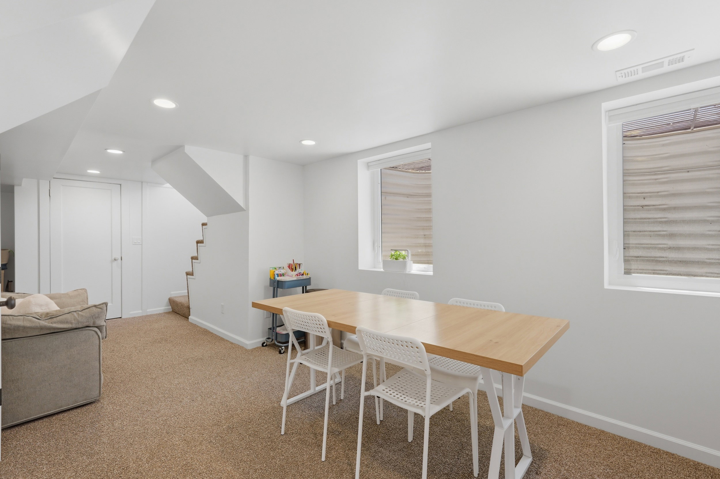 Carpeted lower level featuring white walls, recessed lighting, and a visible staircase