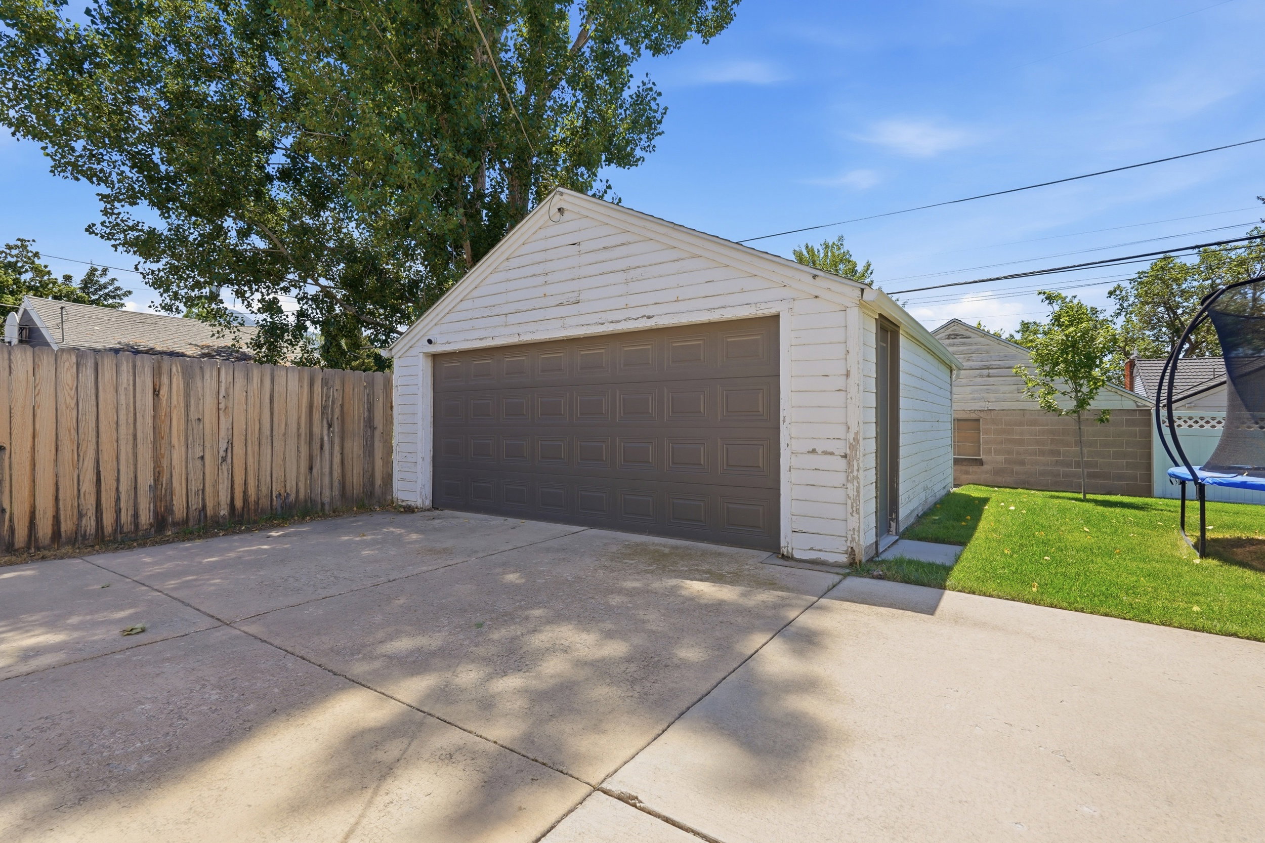 Detached garage with a dark brown garage door, concrete driveway, and side access door