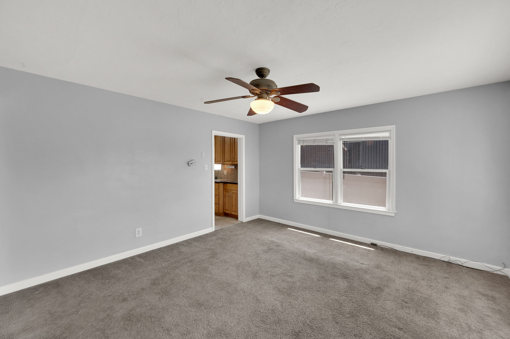 Carpeted room with light gray walls, white trim, and a ceiling fan with integrated lighting