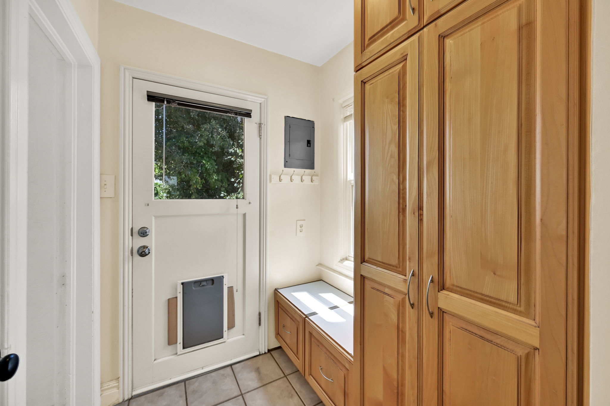 Entryway featuring extensive built-in cabinetry, tile flooring, a window, and a built-in bench with storage