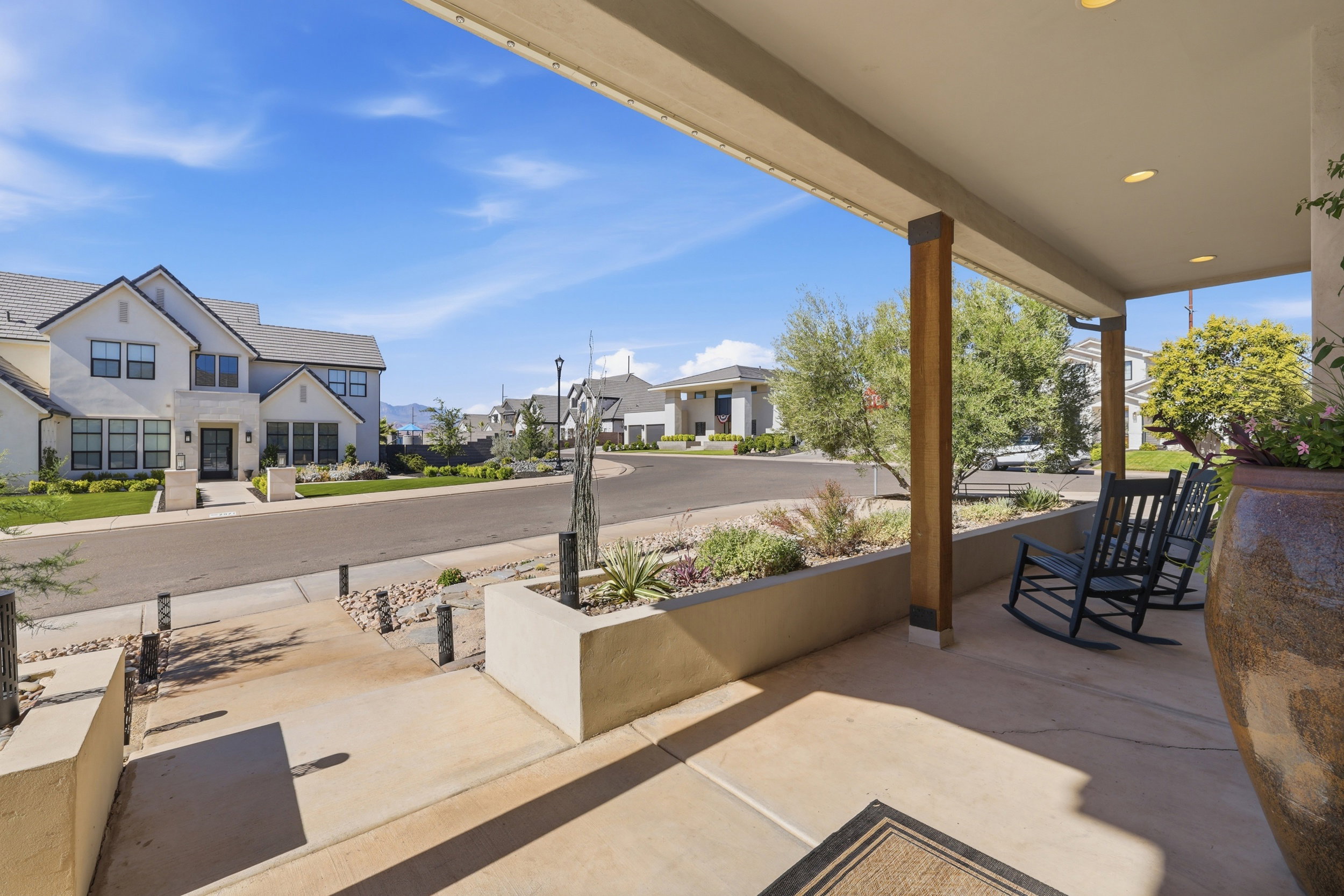 Covered front porch featuring recessed lighting, exposed wood support beams, and a concrete patio