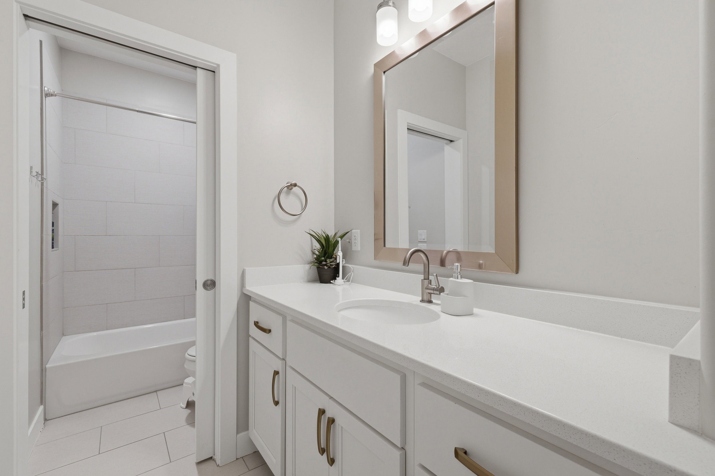 Contemporary bathroom featuring a white vanity with integrated sink, a large framed mirror, and brushed nickel fixtures
