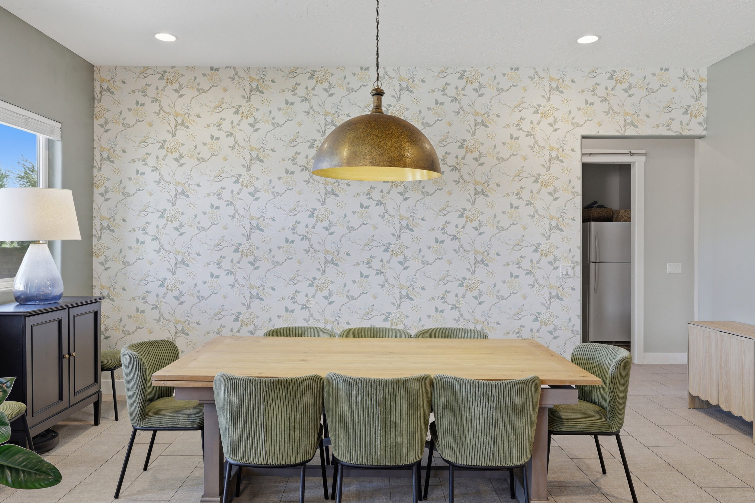 Dining area featuring a prominent floral accent wall, recessed lighting, and a large window with natural light