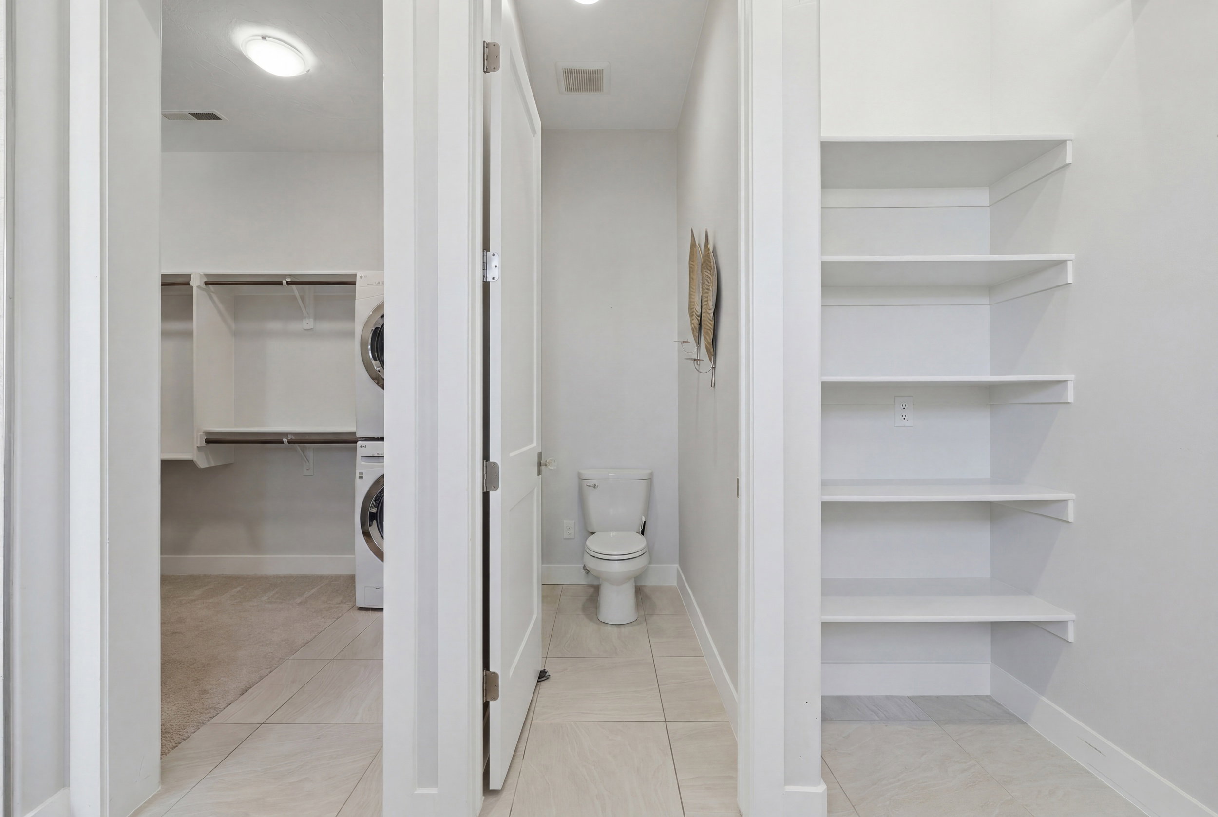 Dedicated laundry area with stacked appliances and built-in shelving, complemented by a separate toilet room
