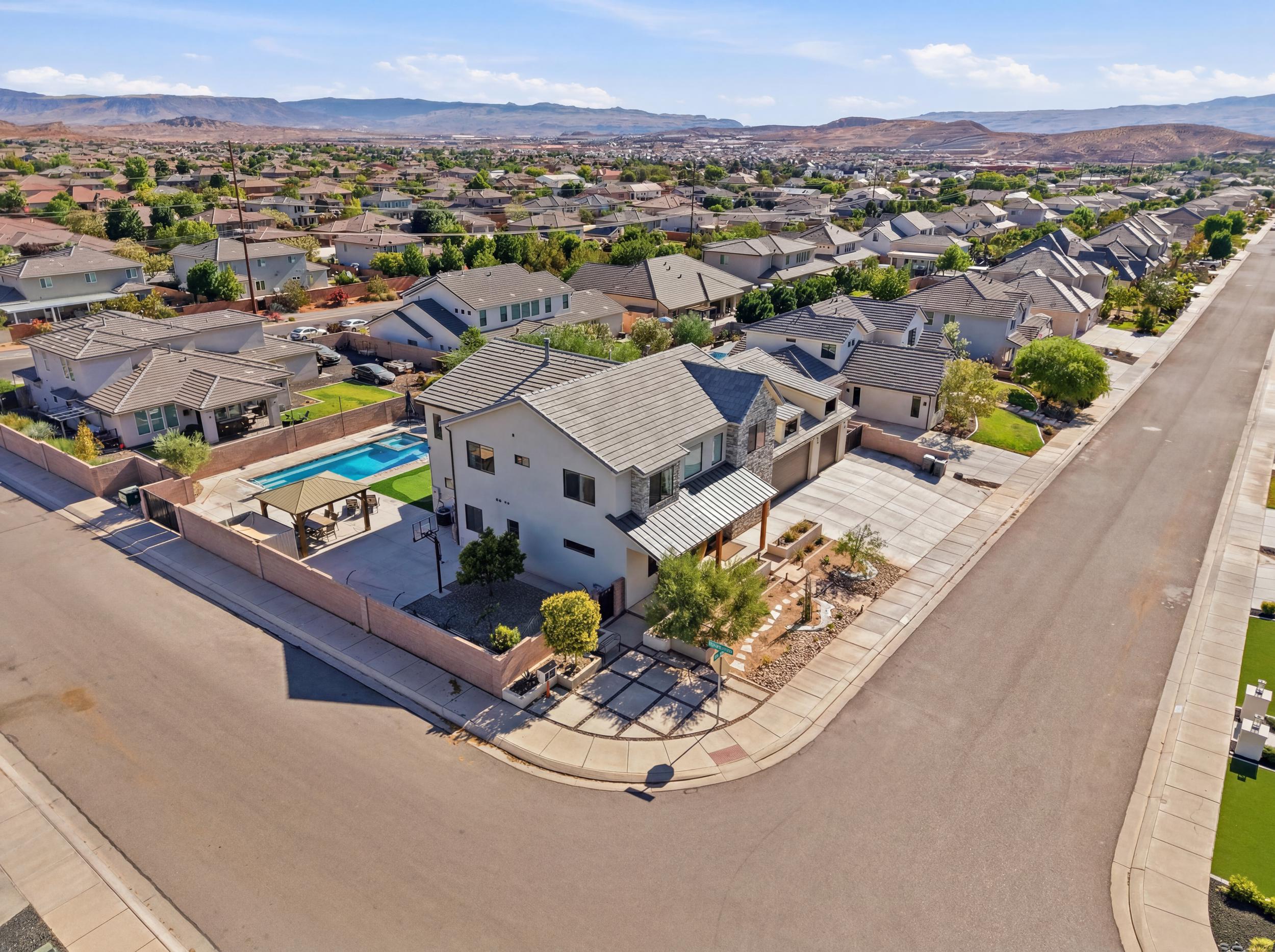 Corner property featuring a stucco exterior with stone accents, a multi-car driveway, and an inground swimming pool