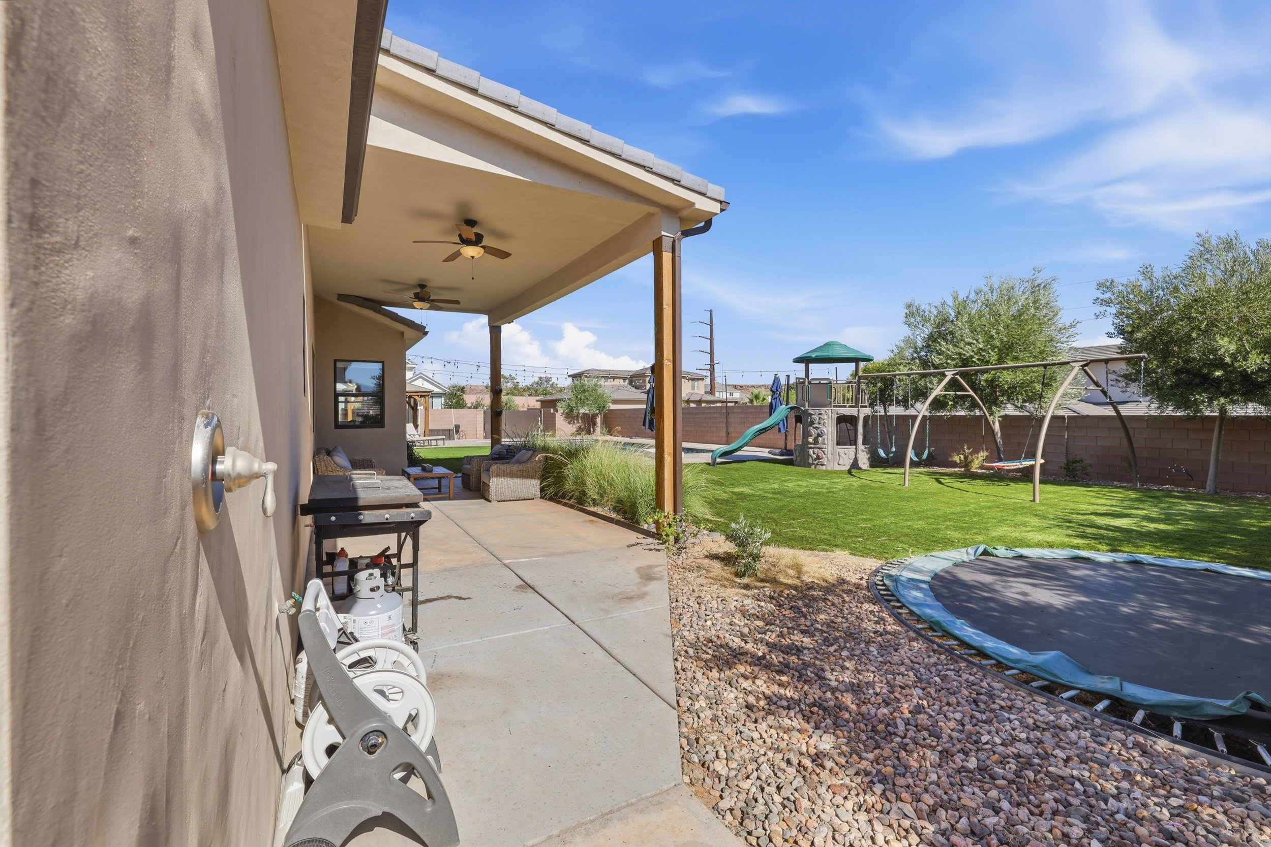 Covered patio featuring wood-finish ceiling fans, concrete flooring, and wood-wrapped columns