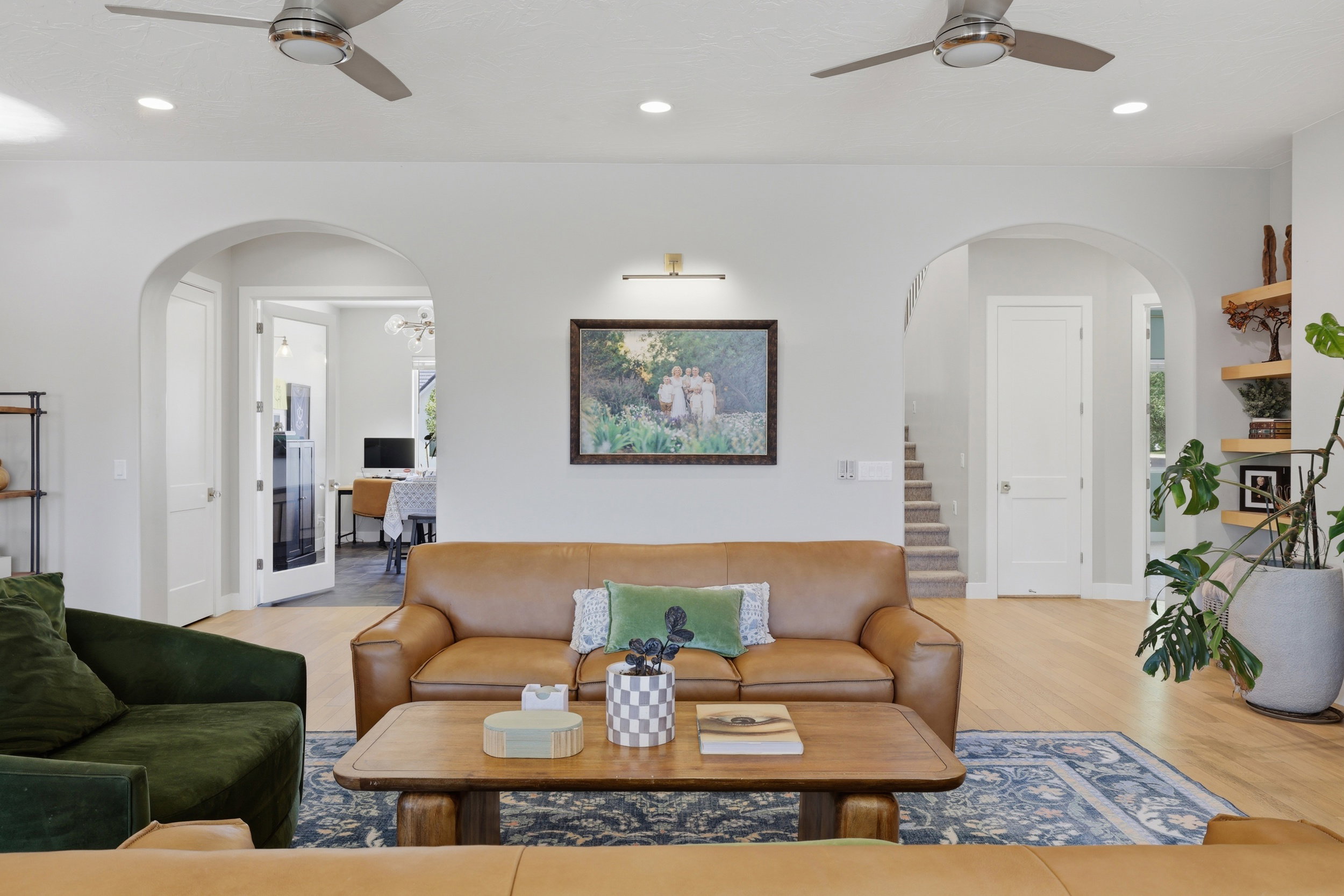 Spacious living area featuring light wood-finish flooring, recessed lighting, and two ceiling fans