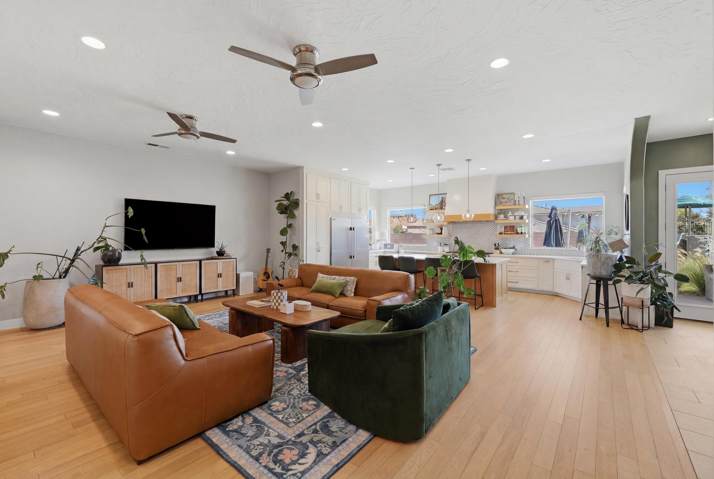 Open-concept living space featuring light wood-finish flooring, recessed lighting, and ceiling fans
