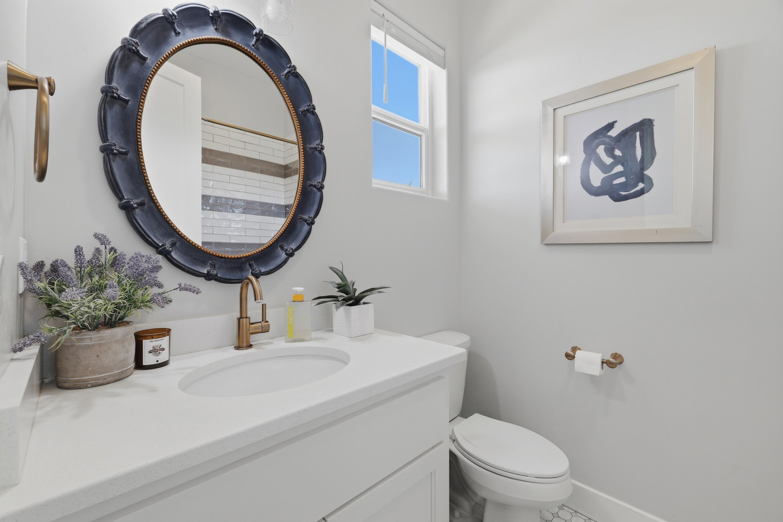 Bathroom vanity featuring a white countertop, an undermount sink, and a gold-finish faucet