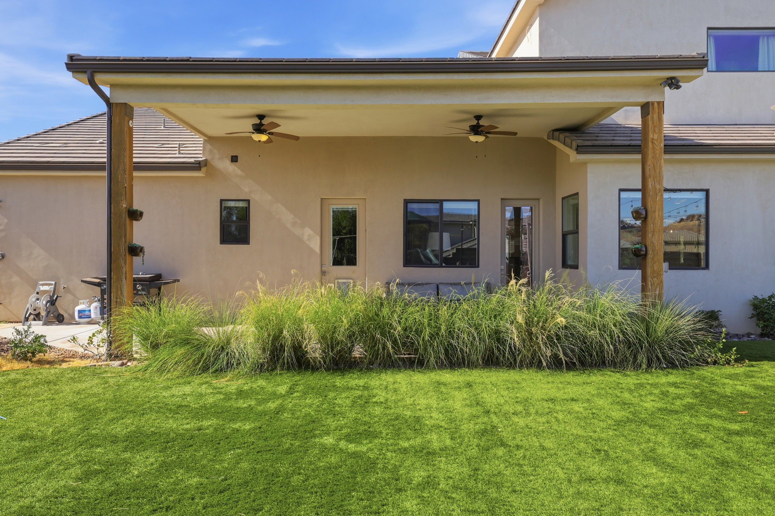Covered patio featuring two ceiling fans and wood support columns