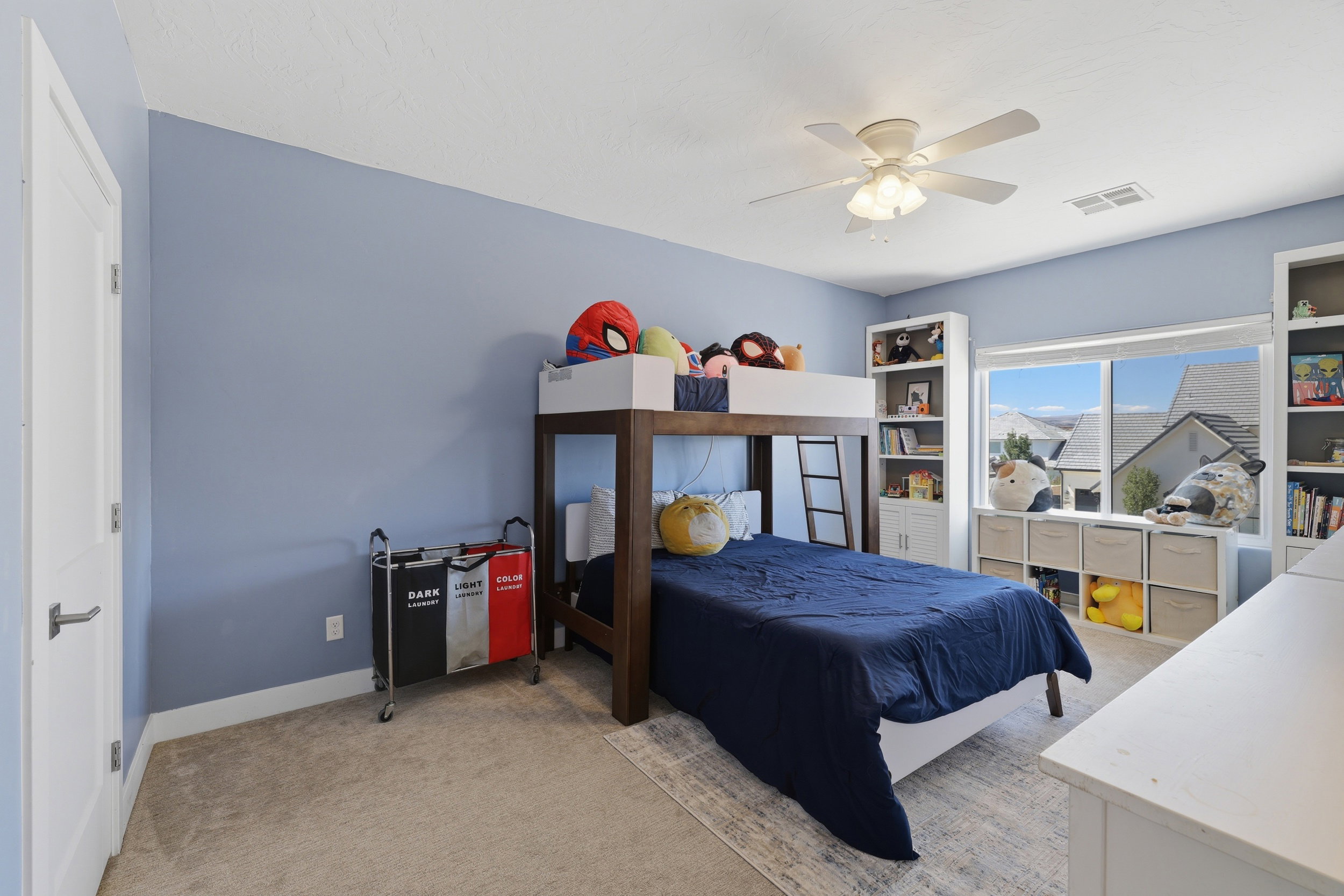 Bright room featuring a large window, light-colored carpet, a ceiling fan, and built-in shelving