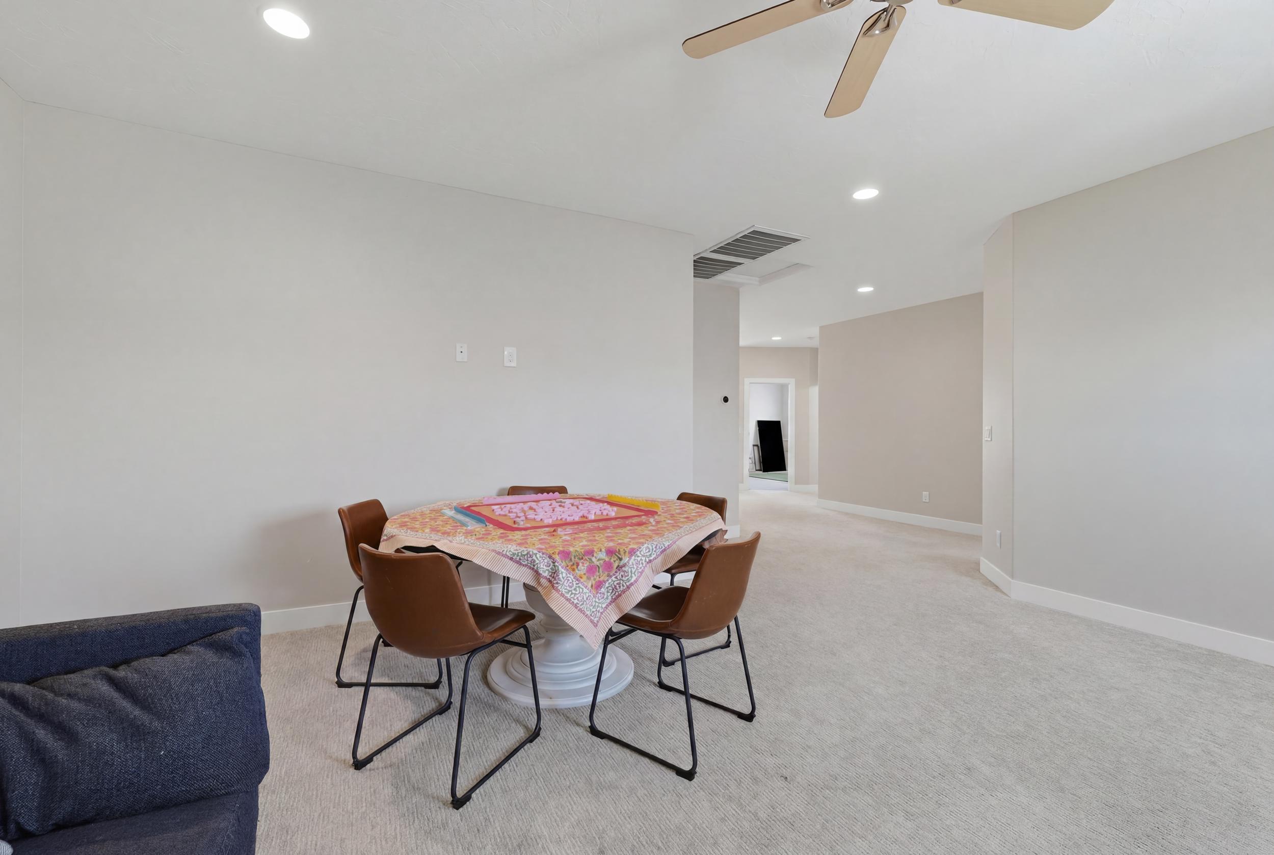 Spacious room featuring neutral carpeting, light-toned wall paint, recessed lighting, and a ceiling fan
