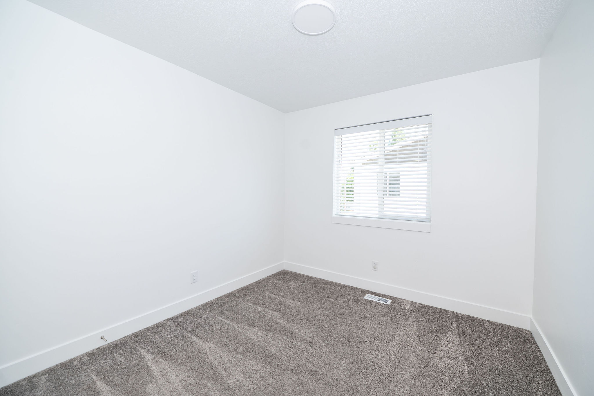 Room featuring grey carpeting, white baseboards, and a window with blinds